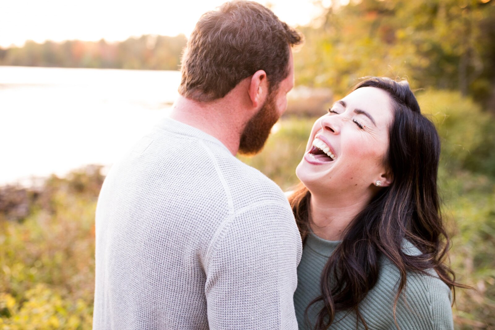 Couple laughing together in front of Pinehurst Lake during engagement session.