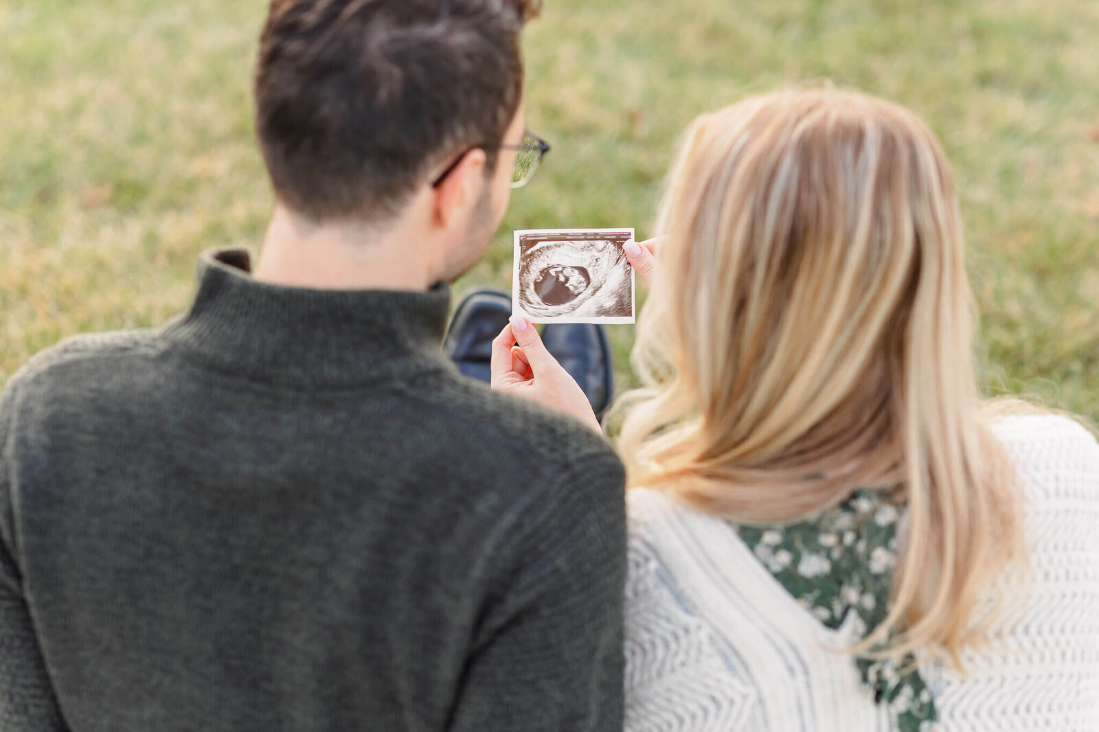 A view from behind of mom and dad looking at a sonogram.