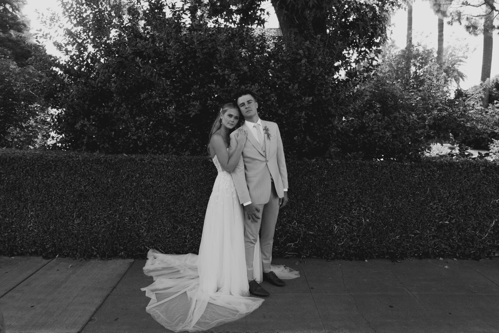 Bride and groom pose in front of hedge as a married couple