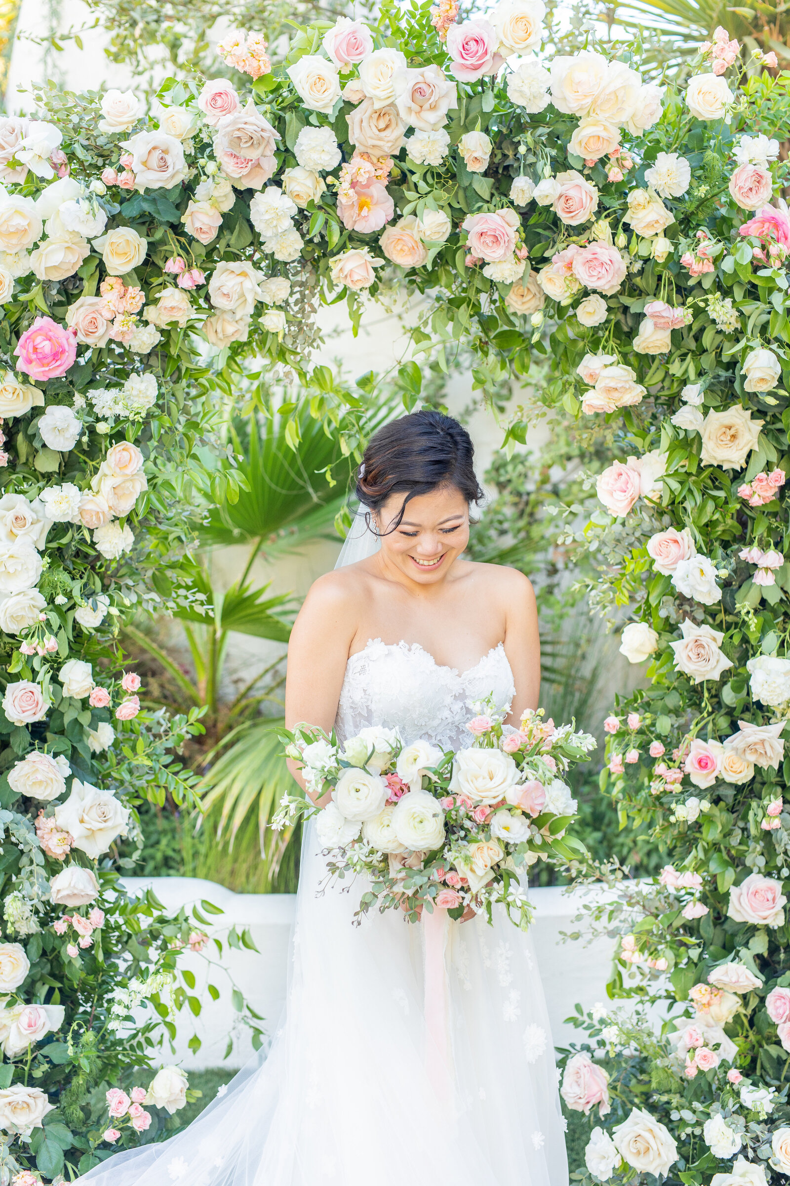 Bride holding bouquet under floral arch from ceremony at Tivoli wedding venue in southern California.