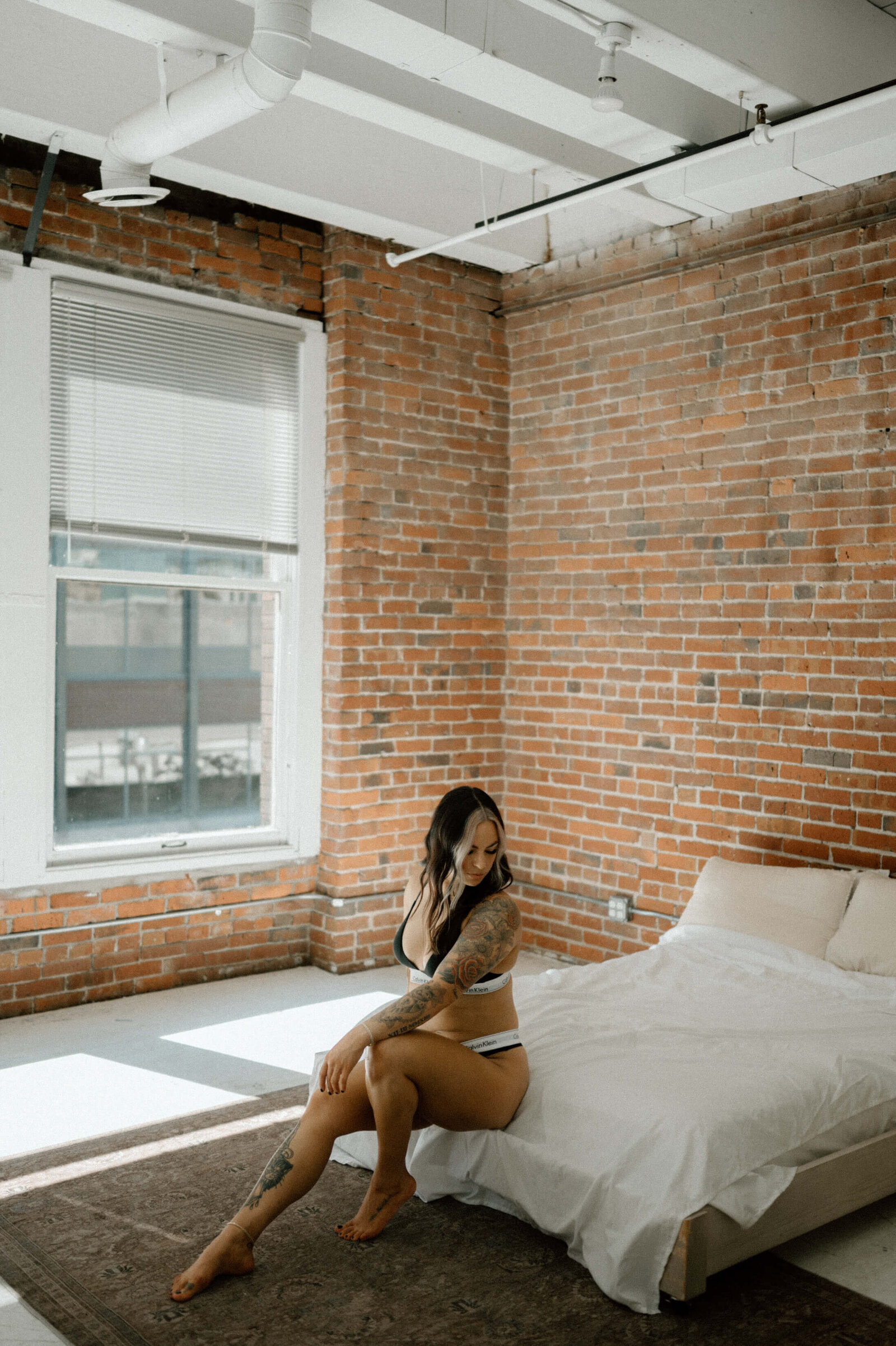 woman sitting on edge of bed in black calvin klein underwear