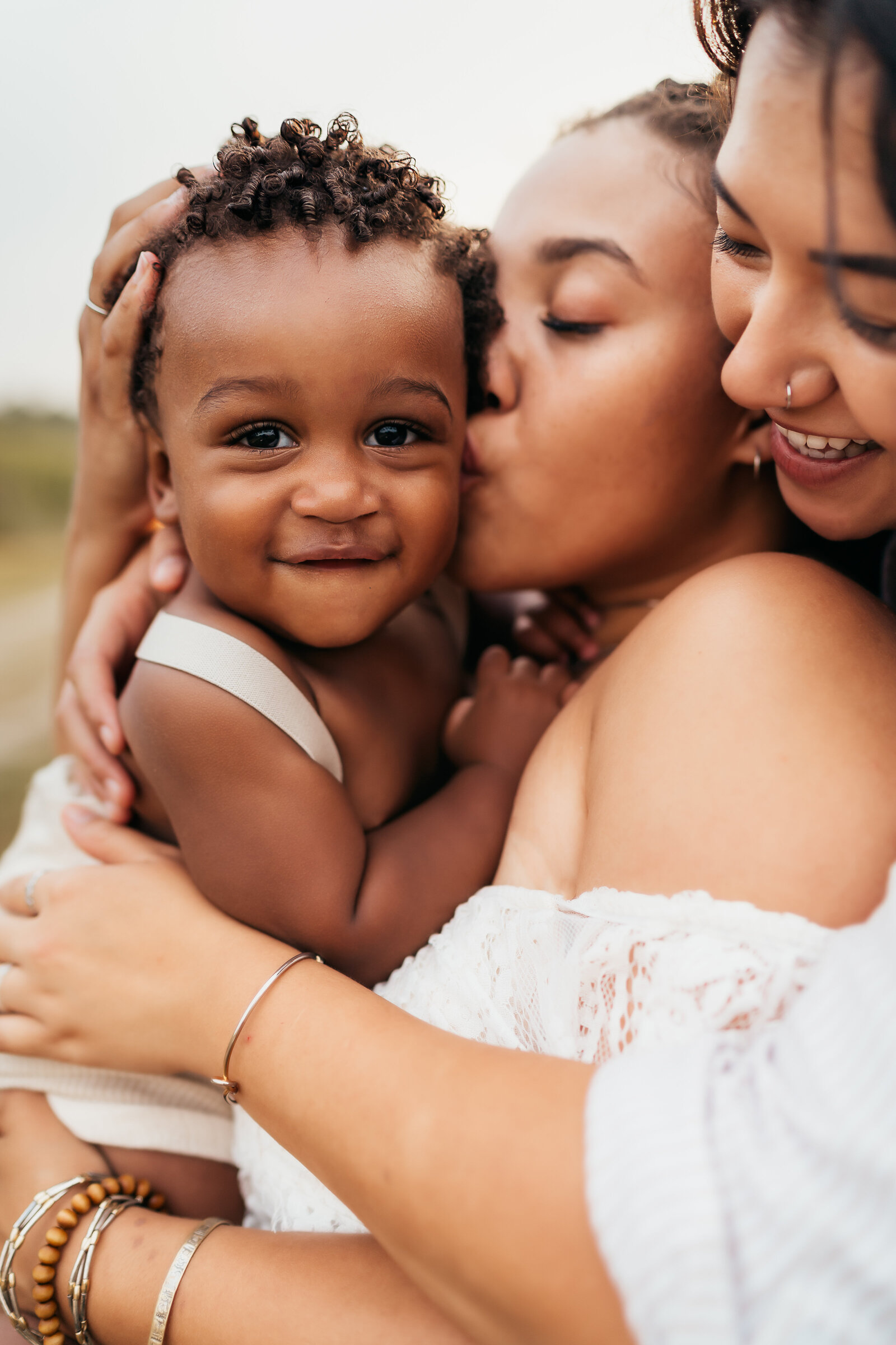 moms holding baby boy and kissing his cheek during a st. louis family photo shoot