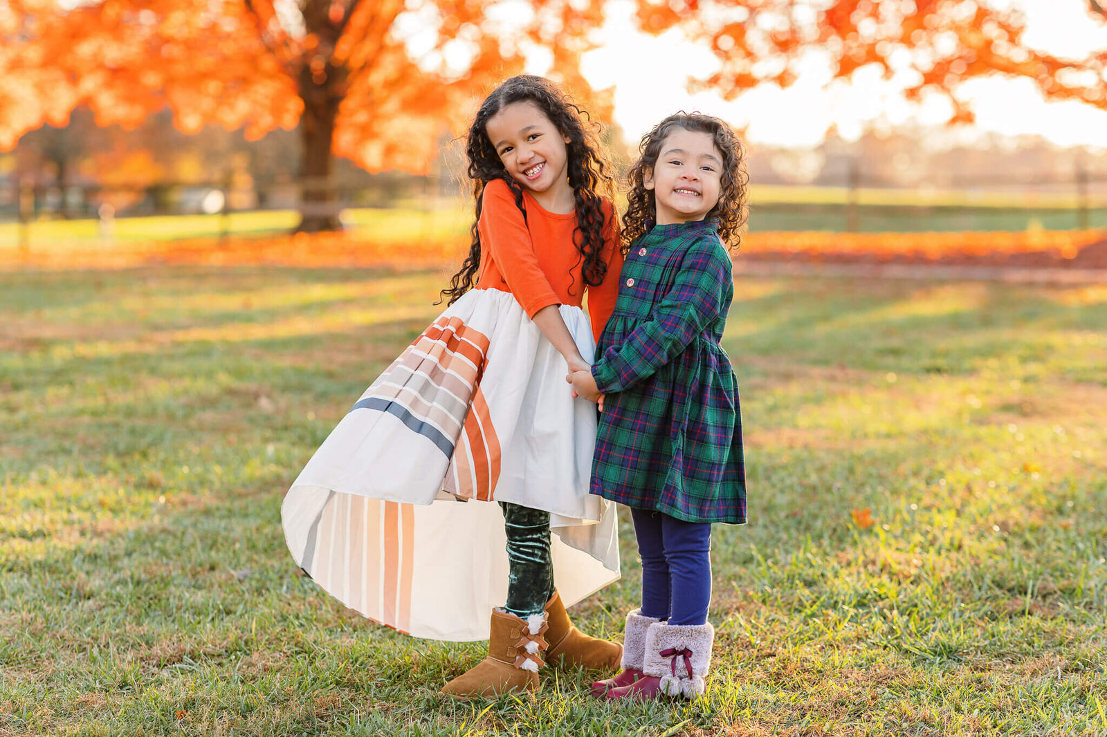 Two sisters posing together among the fall foliage at sunset