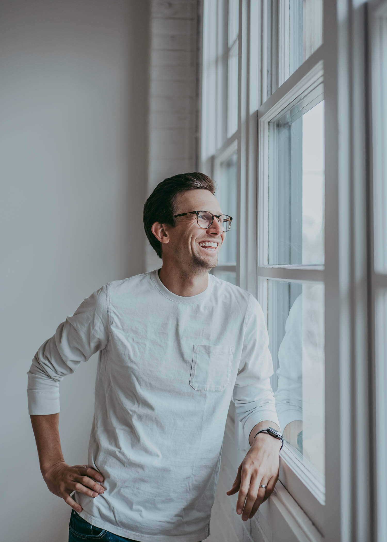 A Denver CEO smiles as he looks out industrial windows in Denver Colorado.