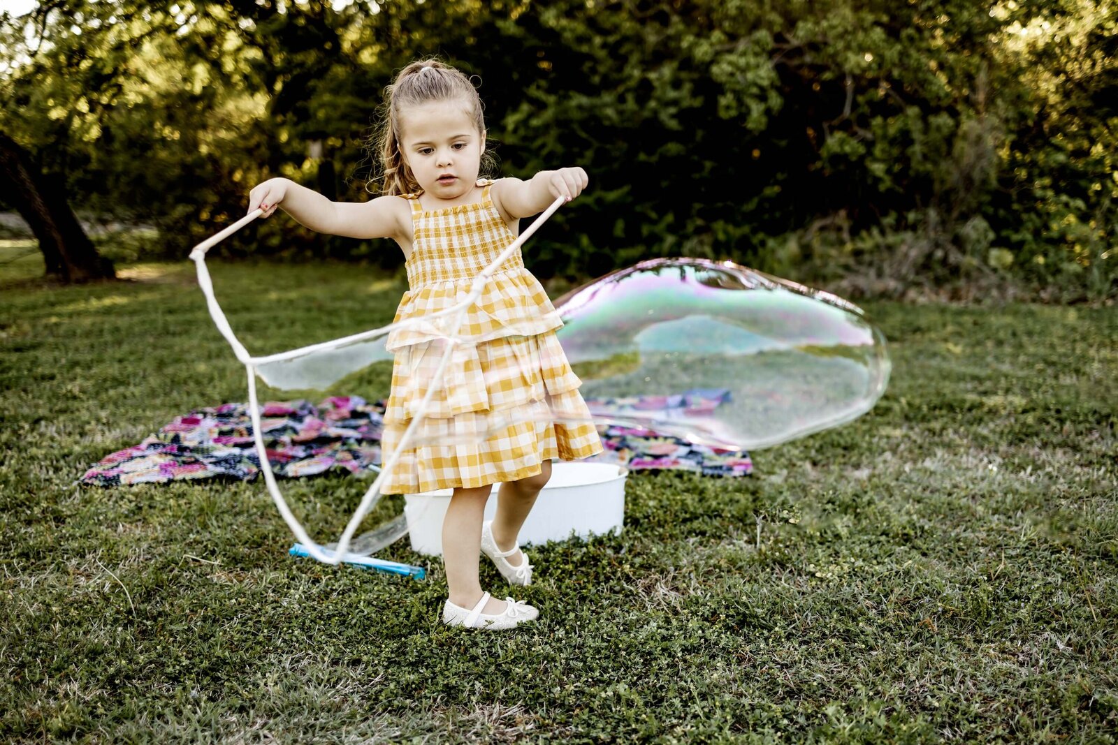 a young girl plays with giant bubbles in the park