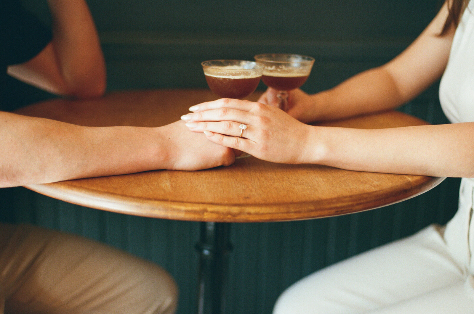 A couple holds hands while sharing an espresso martini at a bar in Halifax. 
