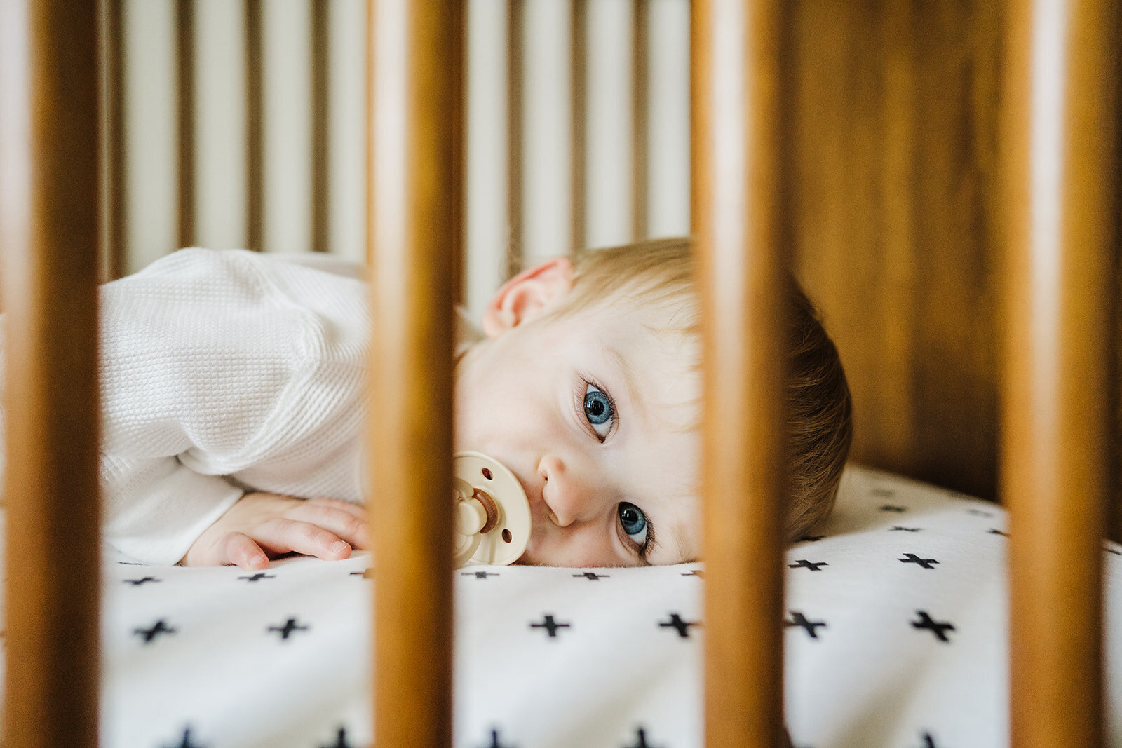 toddler looks through crib bars