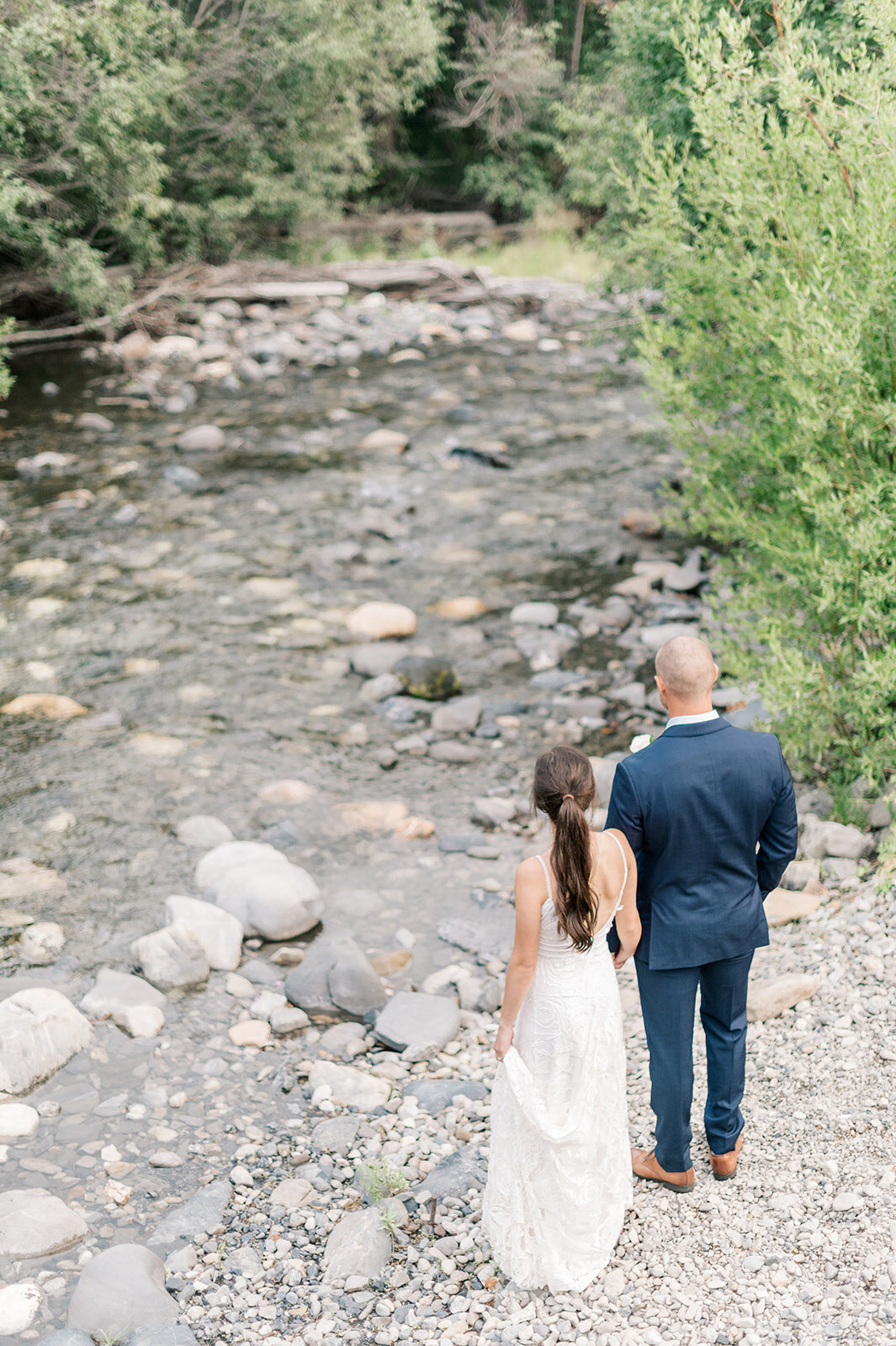 Bride and groom standing next to river or creek at Trail Creek Cabin Wedding taken by the Best Sun Valley Wedding Photographers