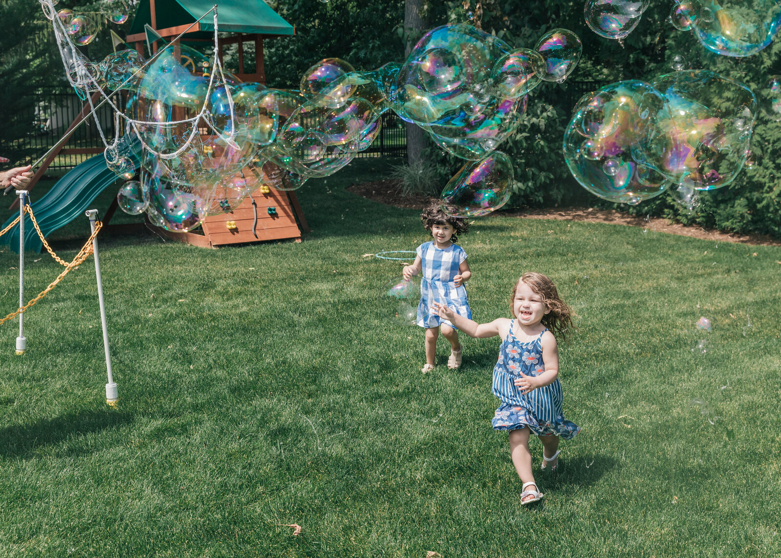 Kids play with giant bubbles at a casual backyard party.