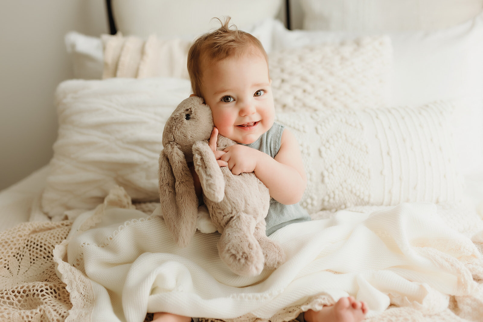 a 9 month old baby girl sits on a bed inside a Vancouver Washington Natural light studio