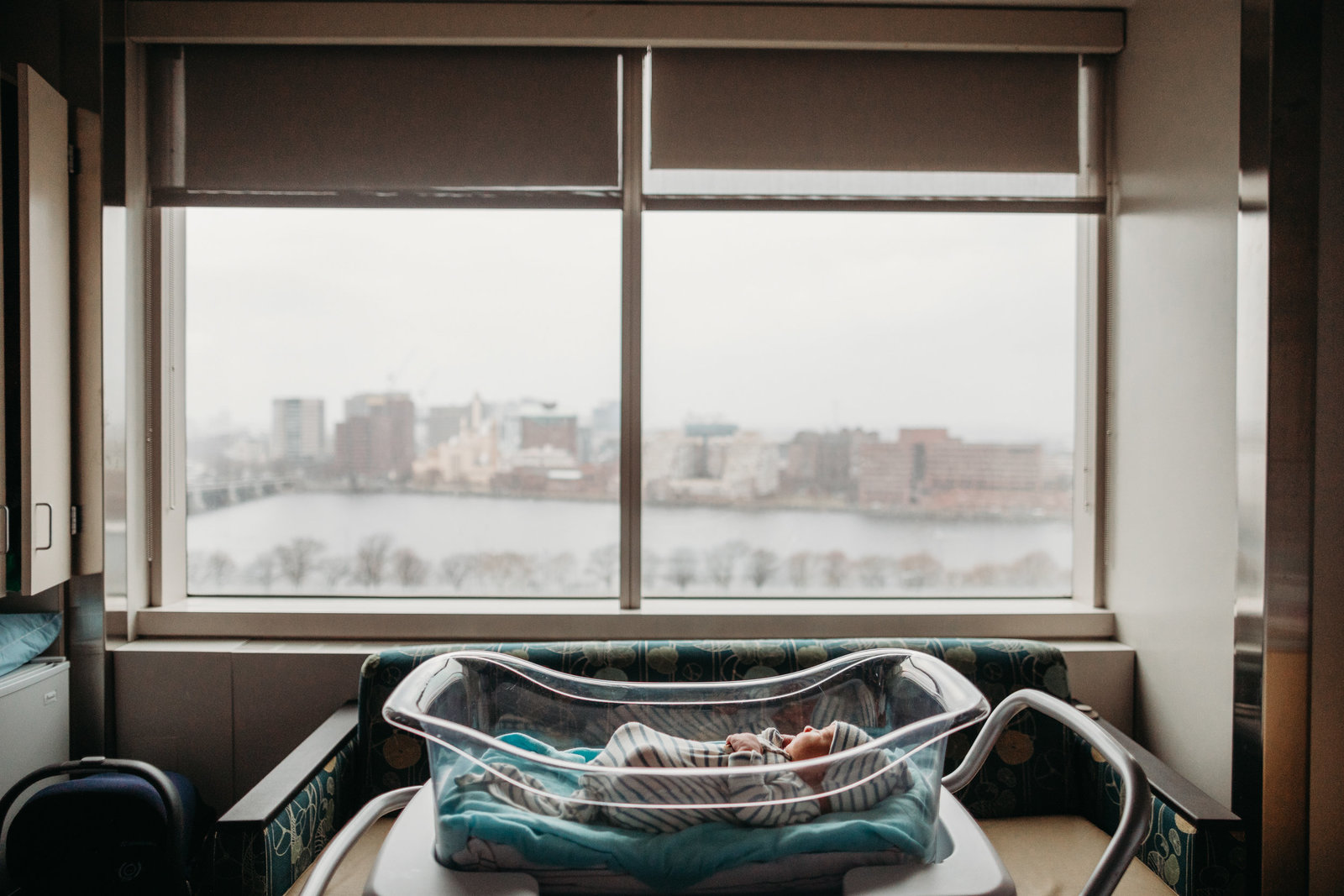 wide angle photo of baby in bassinet in front of hospital room windows