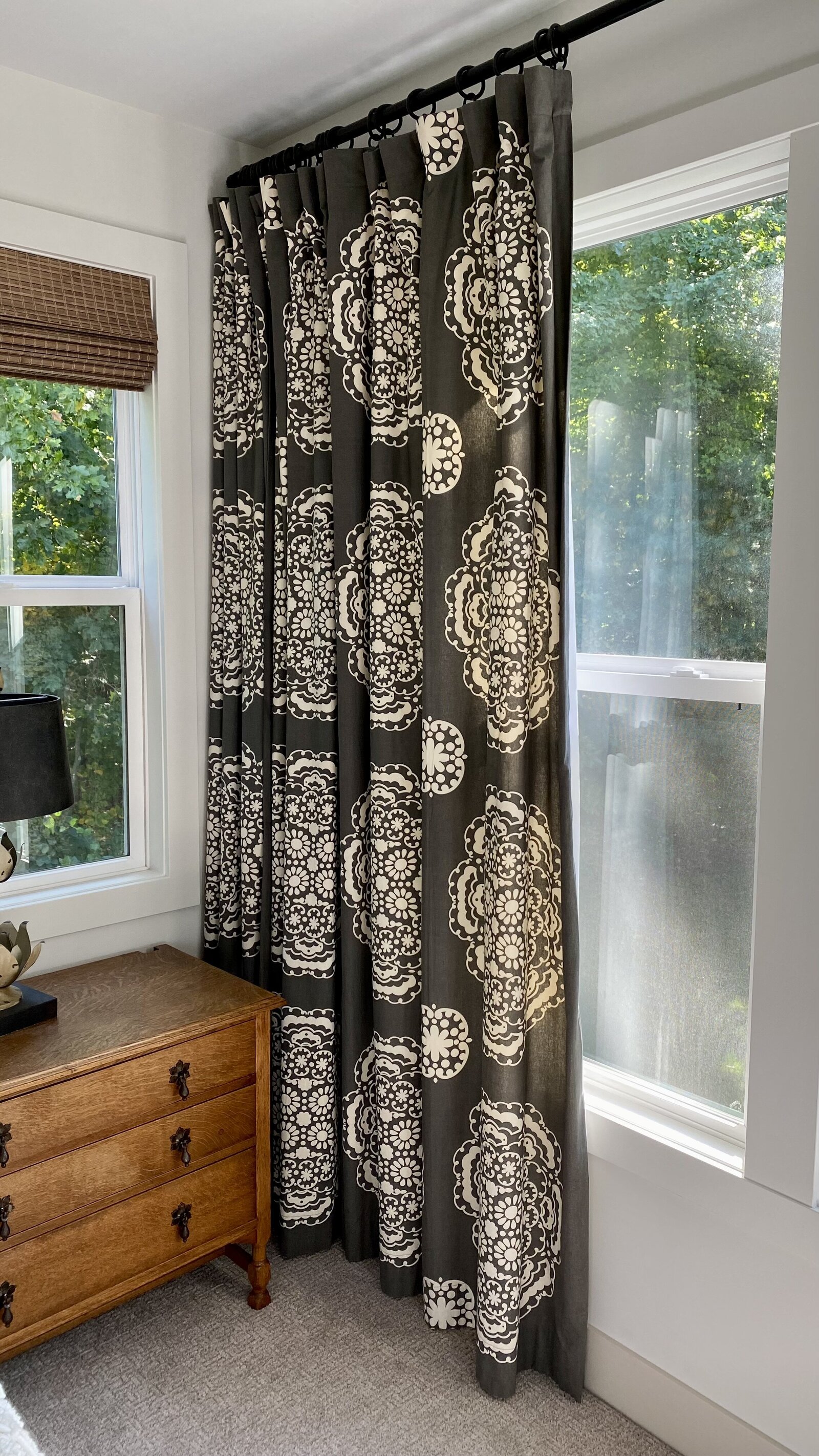 Dark grey and offi white patterened curtains hanging by windows.