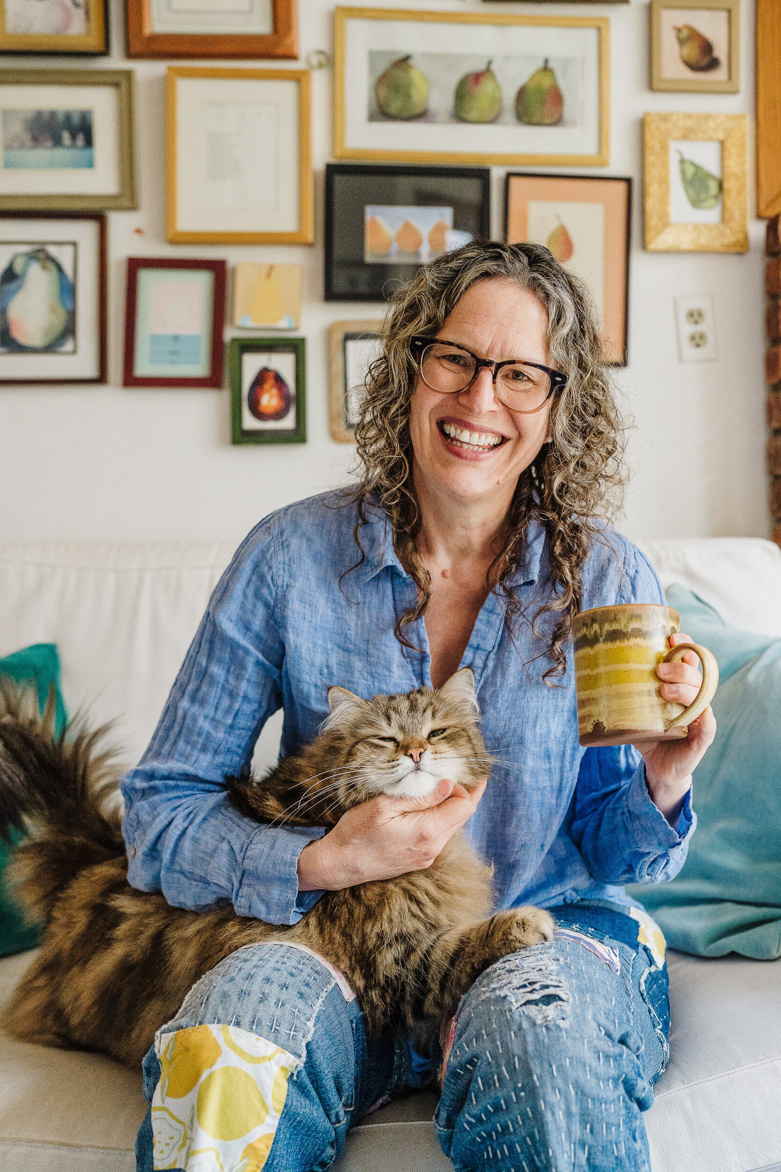 author smiles with cat and coffee mug