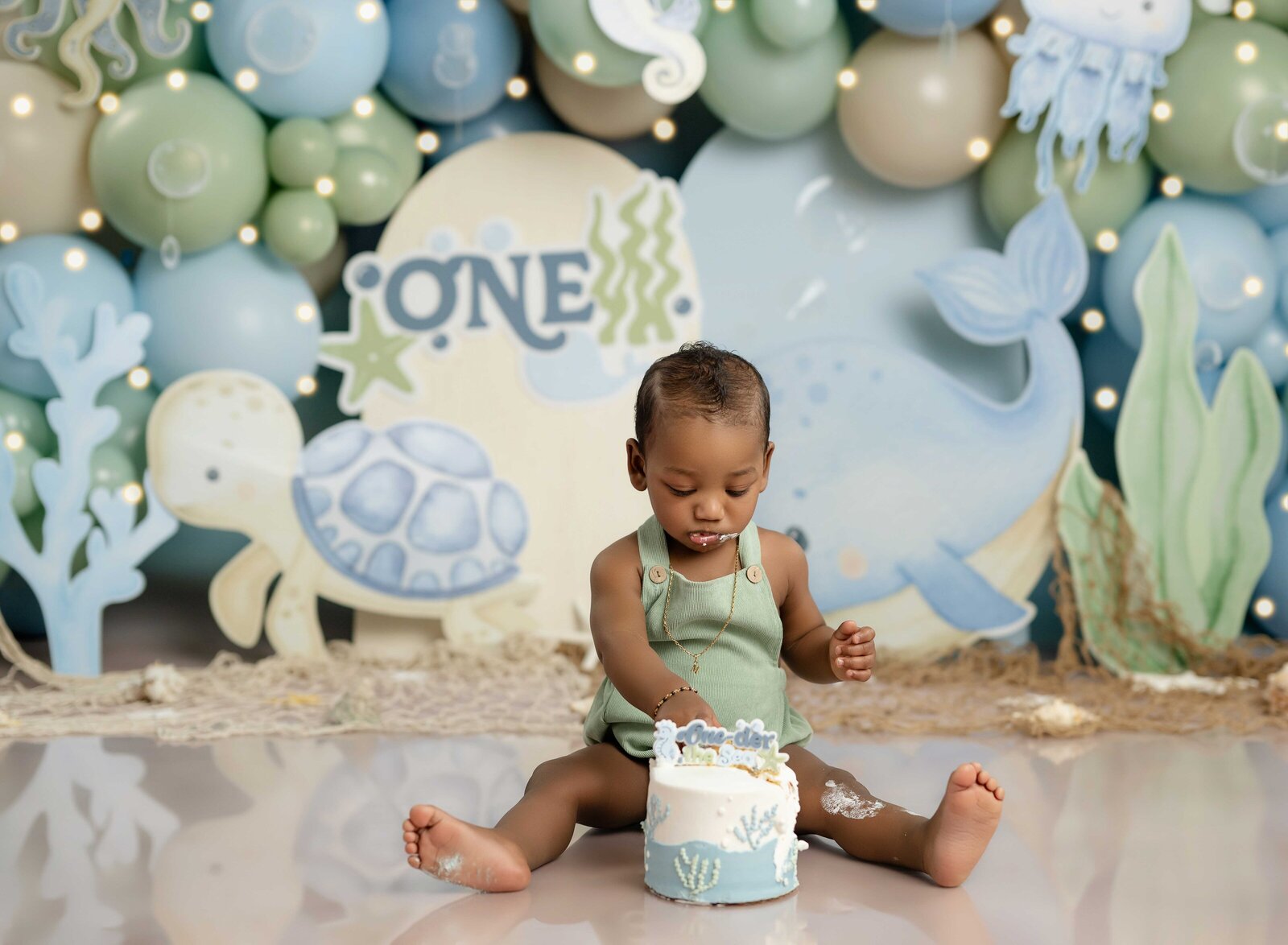 Baby taking cake smash photos in Atlanta and eating under the sea themed cake.