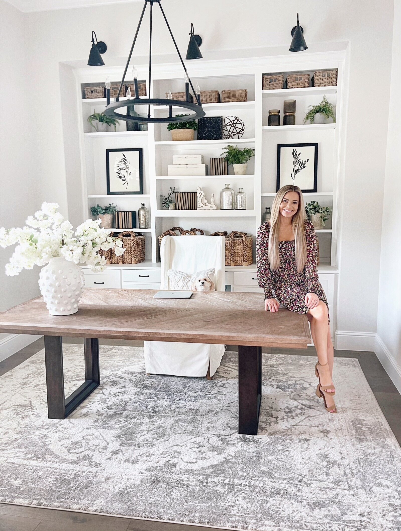 Owner Erin sitting on a desk in an office full of MTH items