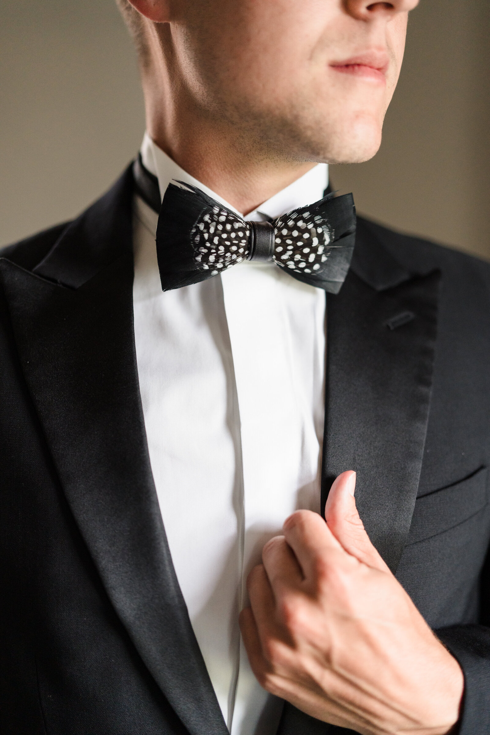 Detail photo of a groom's feather bow tie