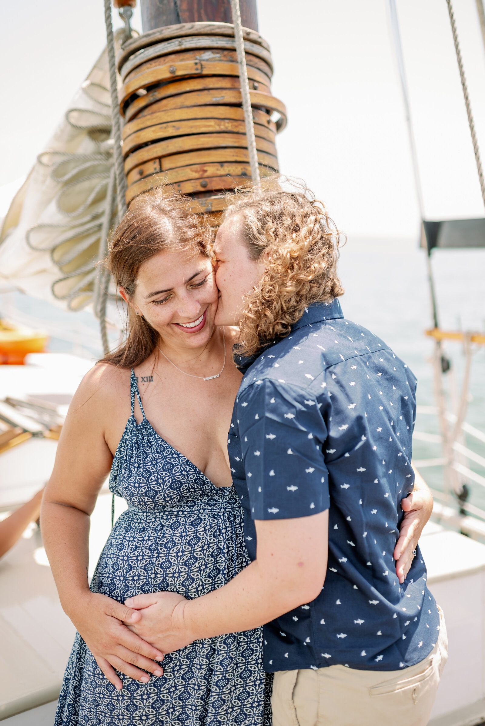 engaged couple sharing a quick kiss on the cheek on the sailboat in Key West, FL