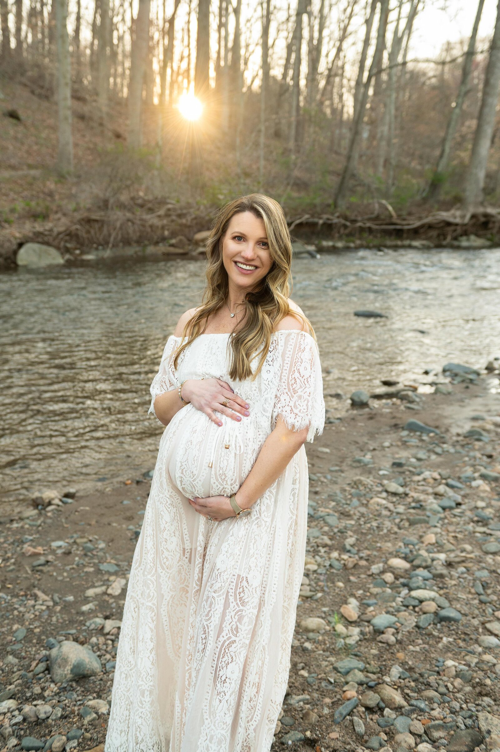 mom at sunset by the river in a white maternity dress