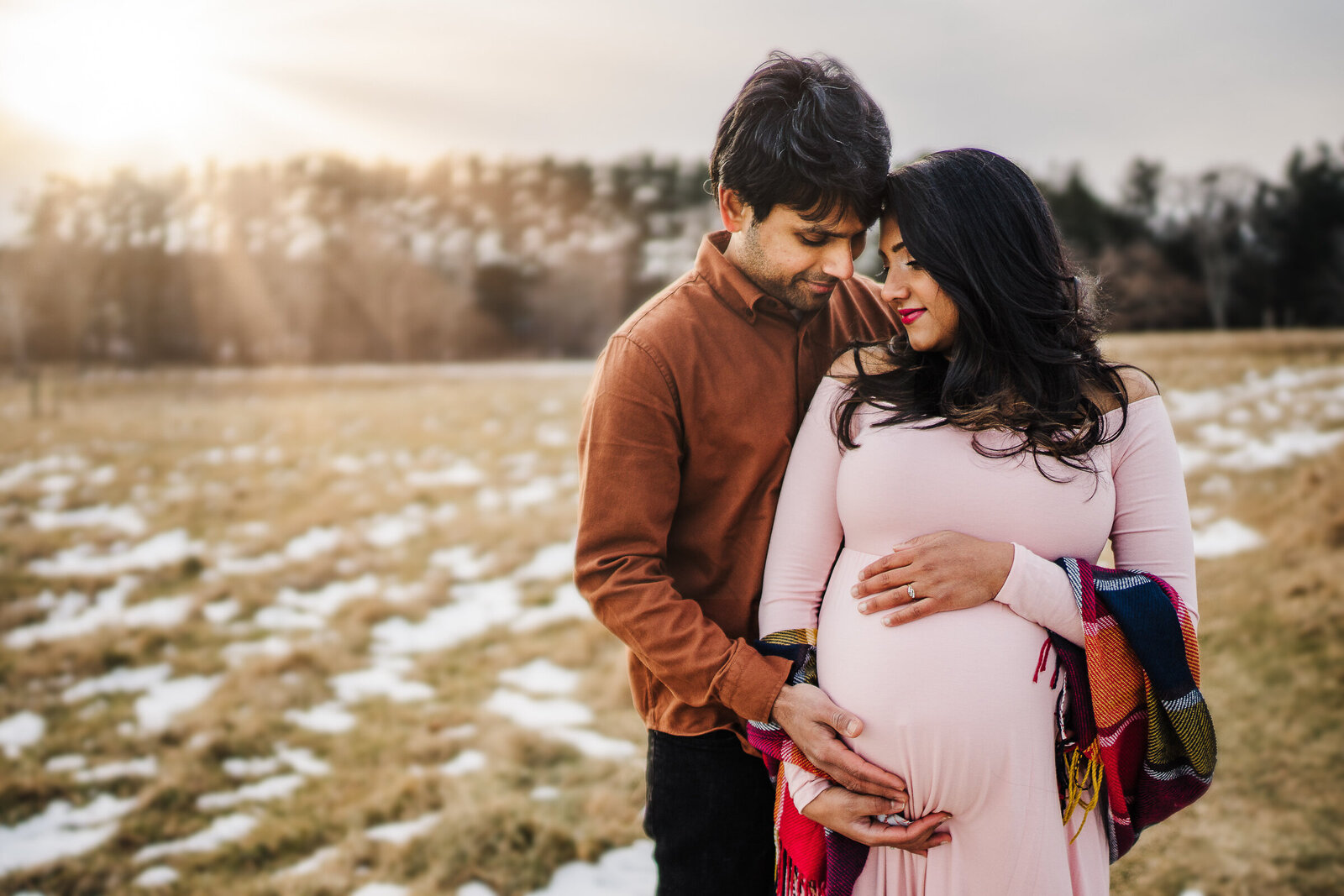pregnant couple in snowy field during boston maternity photos