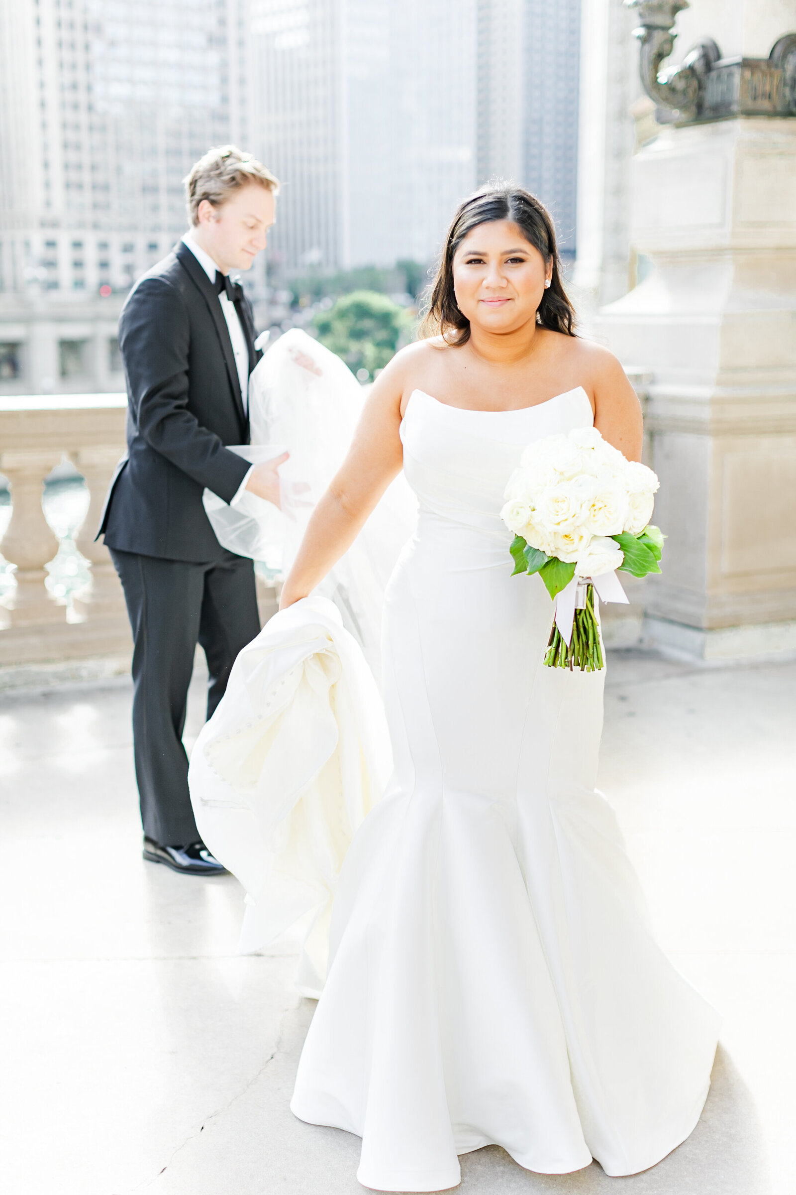 20_groom_helping_bride_with_train_of_dress_wrigley_building_chicago