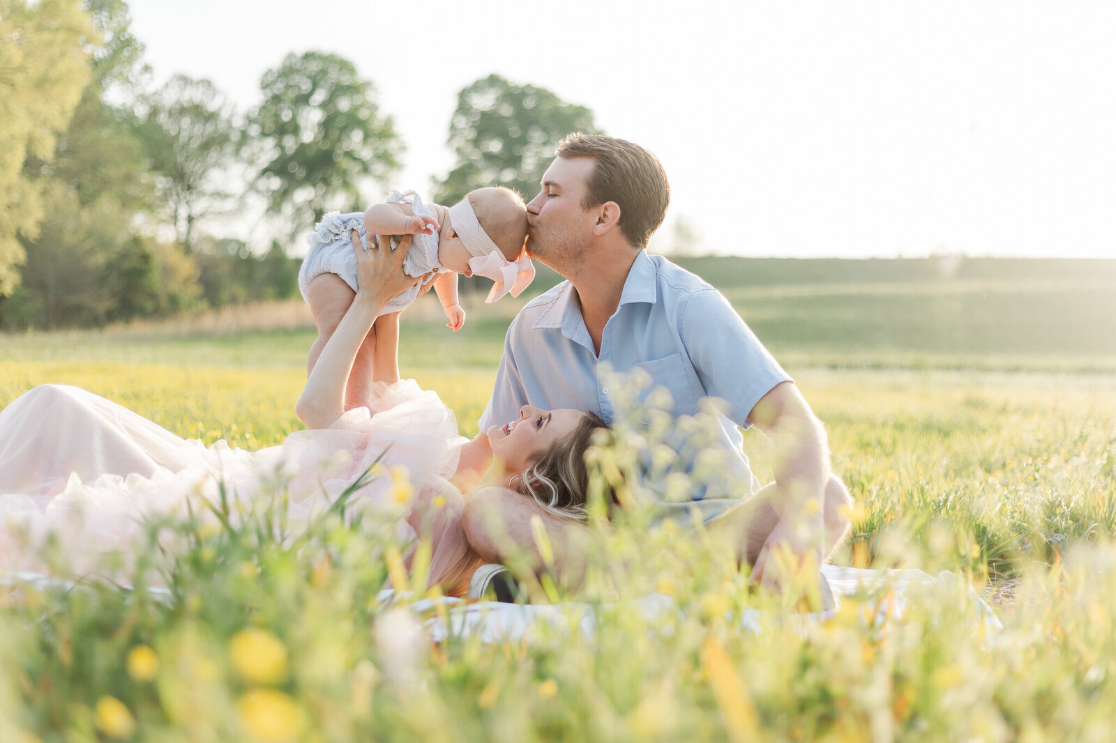 Pregnant woman wearing light pink dress petting horses nose in field during maternity session with 5U Photography in Birmingham, AL