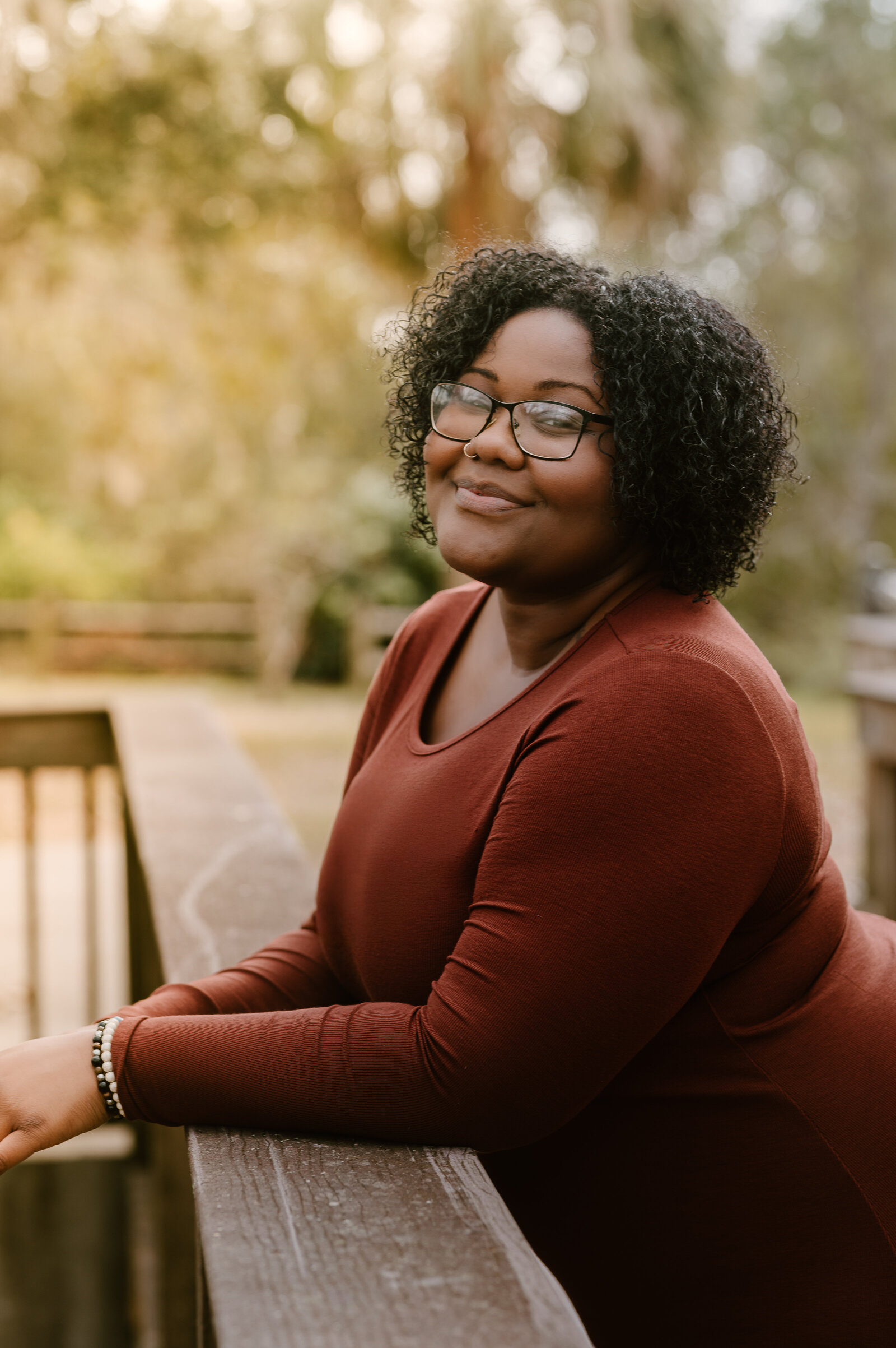 Woman in rust sweater smiling softly during outdoor lifestyle photo session in South Florida