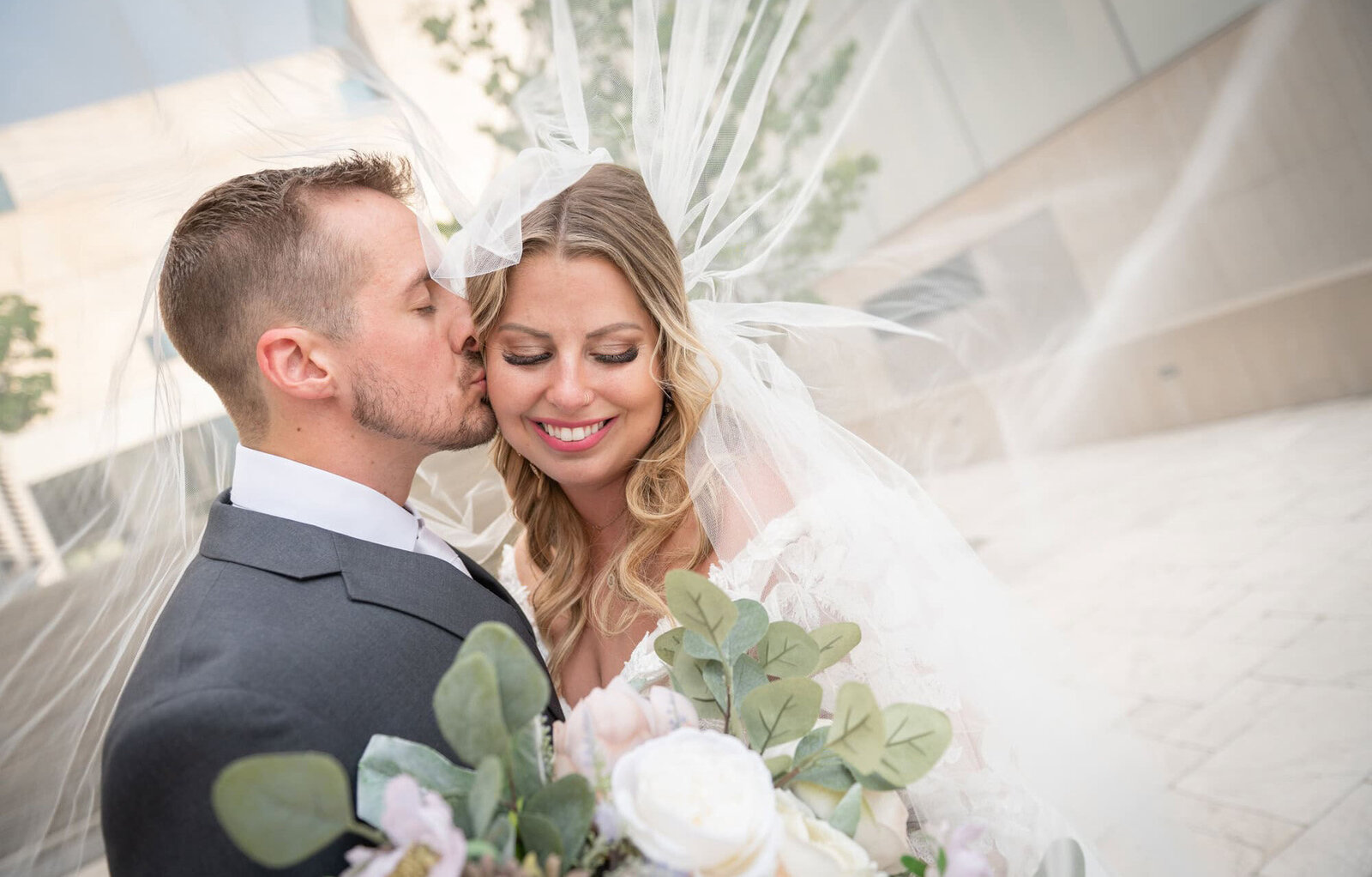 groom kisses bride's cheek under her veil