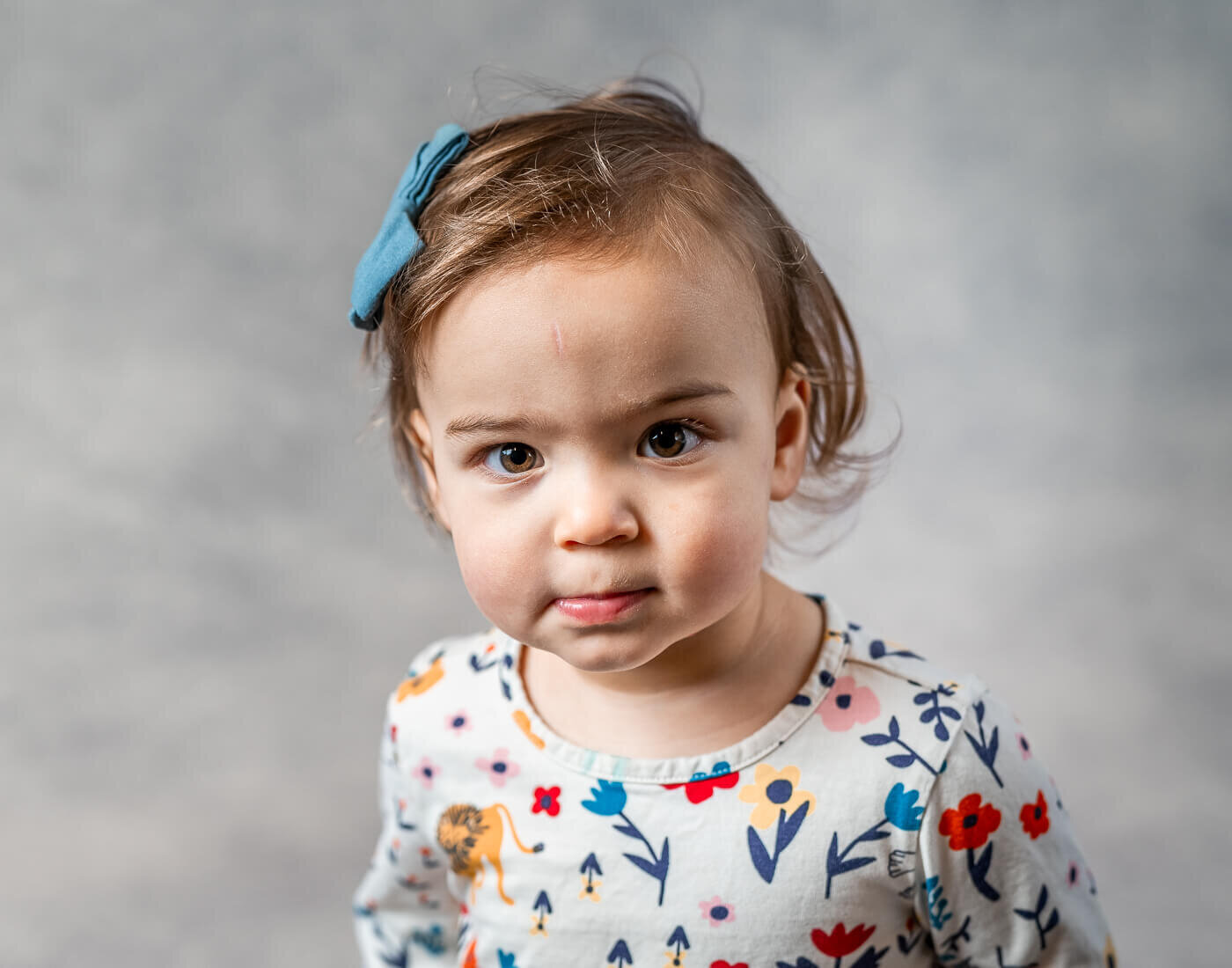 A young girl smiles with a floral shirt.