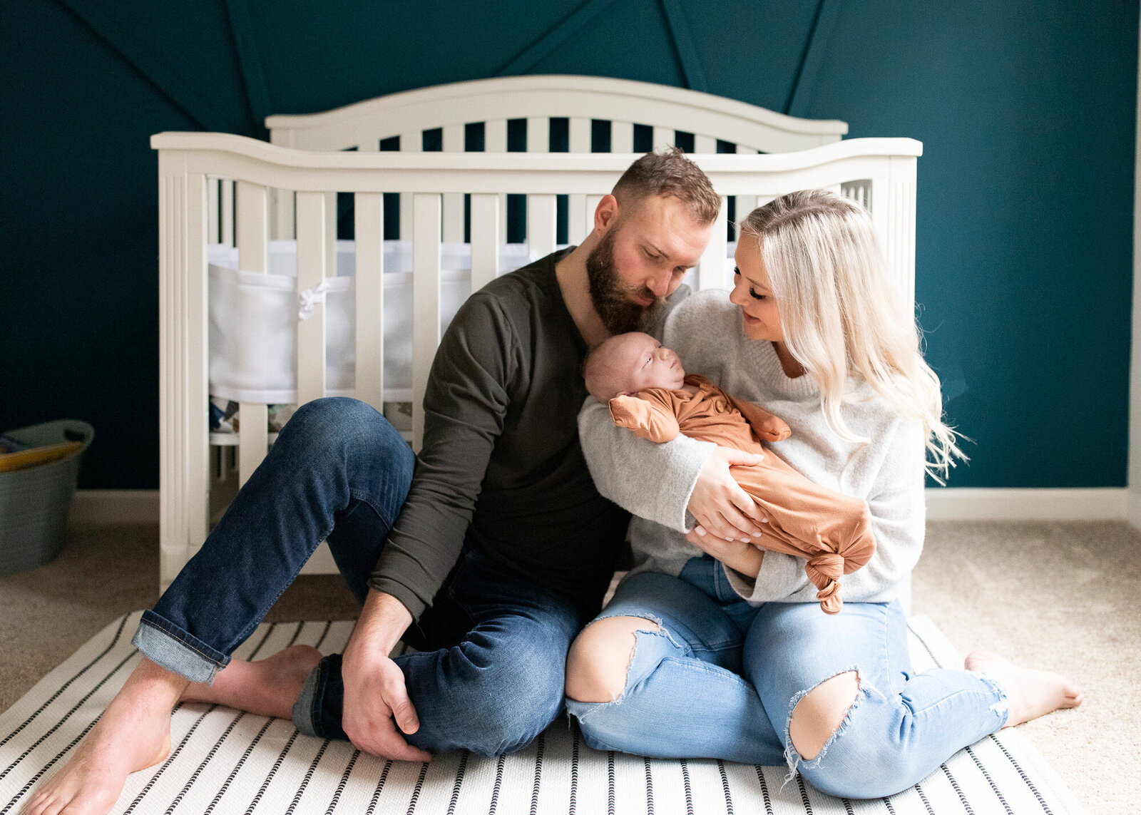 Portland family holding newborn son in teal colored nursery.