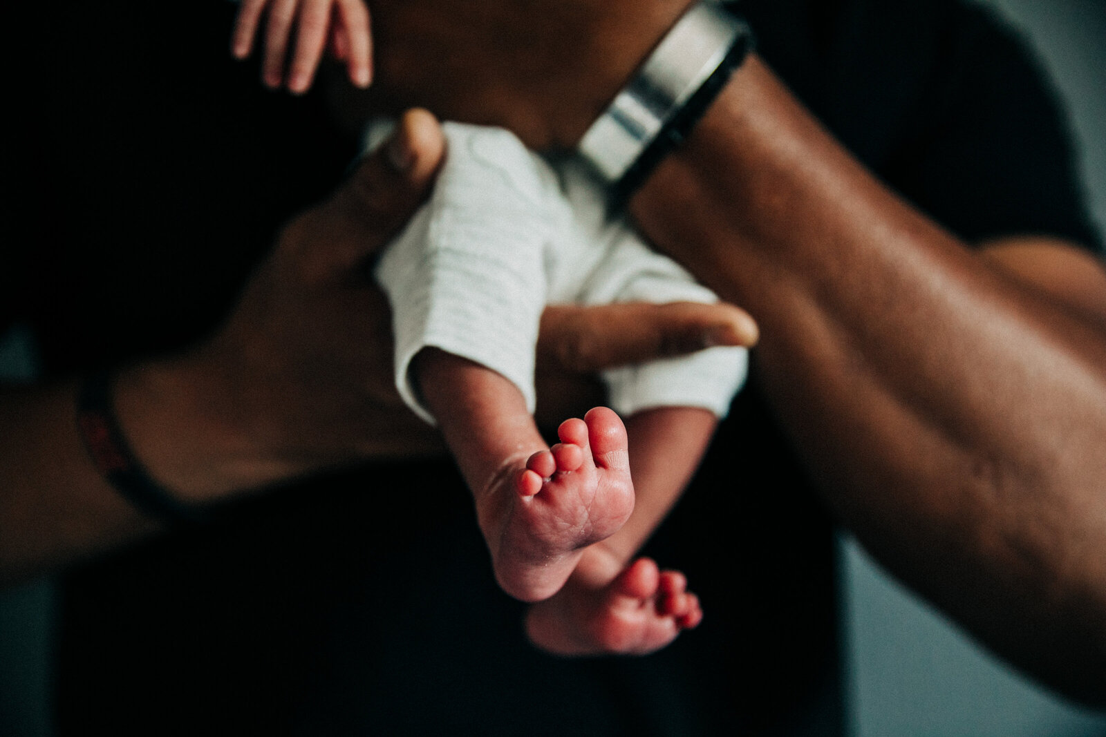 closeup of Black dad holding newborn baby boy with baby toes in focus