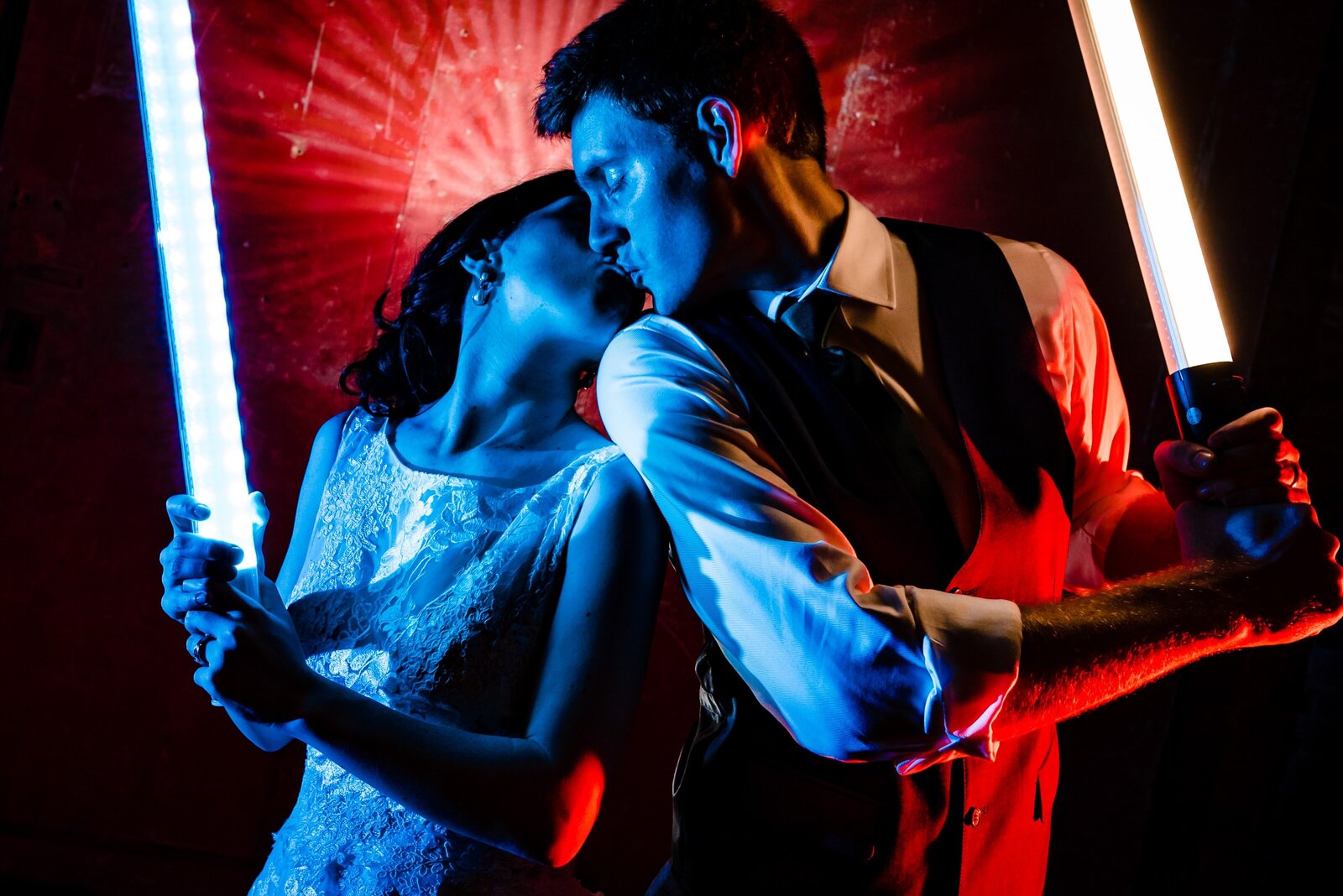 wedding couple poses in a colorful portrait with lightsabers