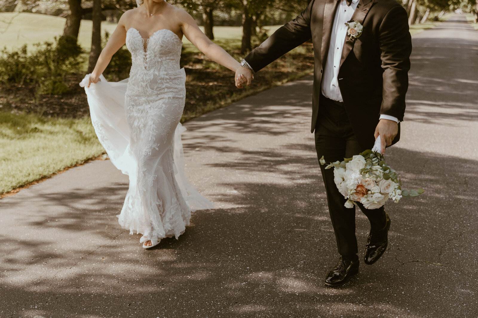 bride and groom walking hand in hand on a paved path