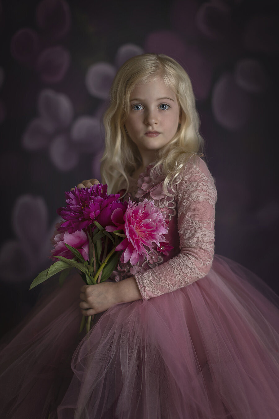 Girl holding flowers in coture gown at Dallas children’s photographer.
