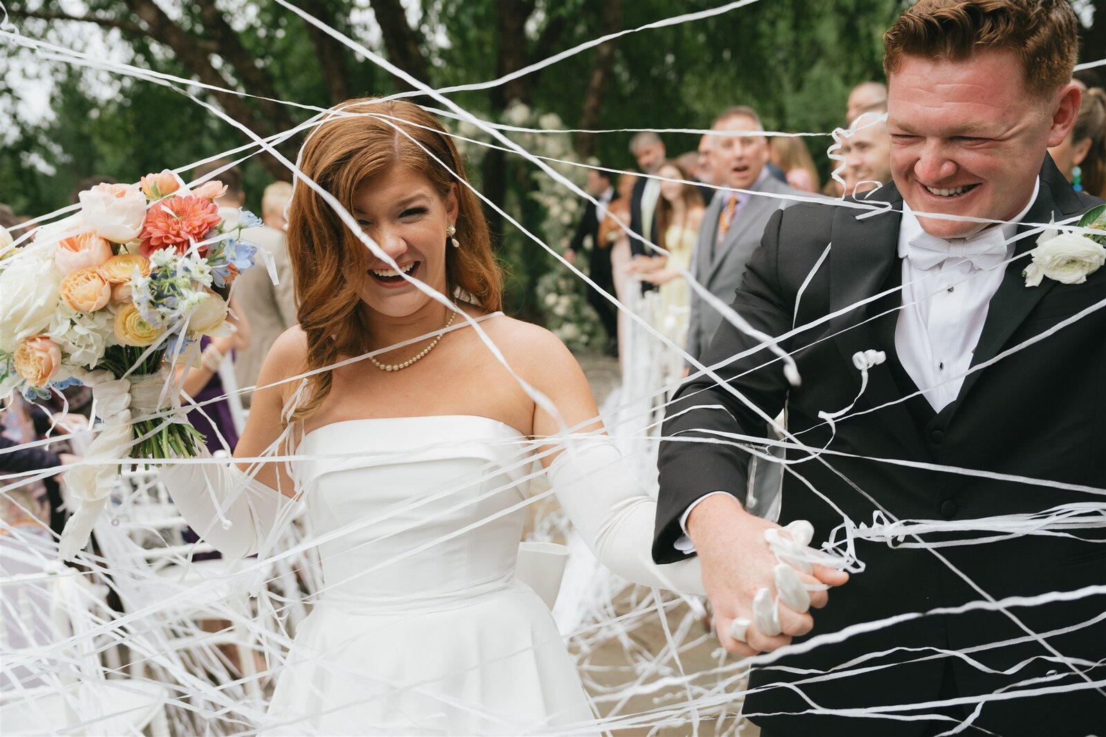 bride and groom walking down the aisle through streamers after ceremony 