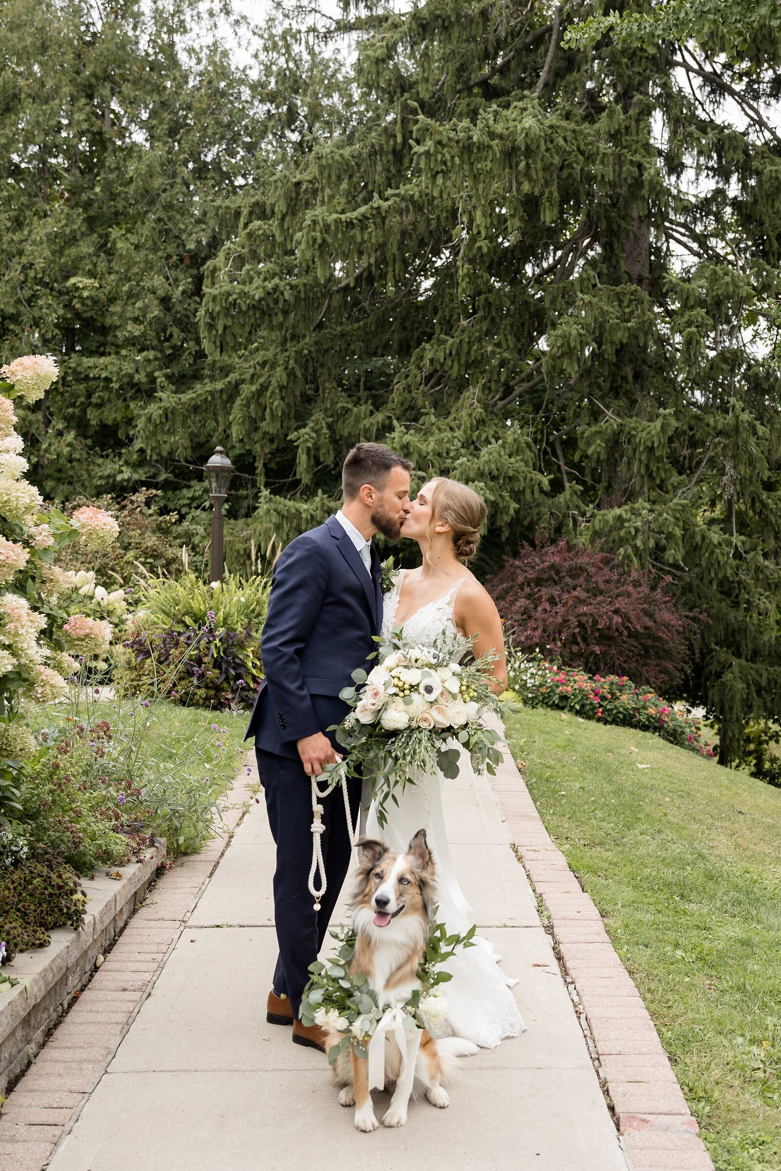Wedding-couple-outside-Elsie-Perrin-Williams-Estate-share-a-kiss-while-their-dog-sits-in-front