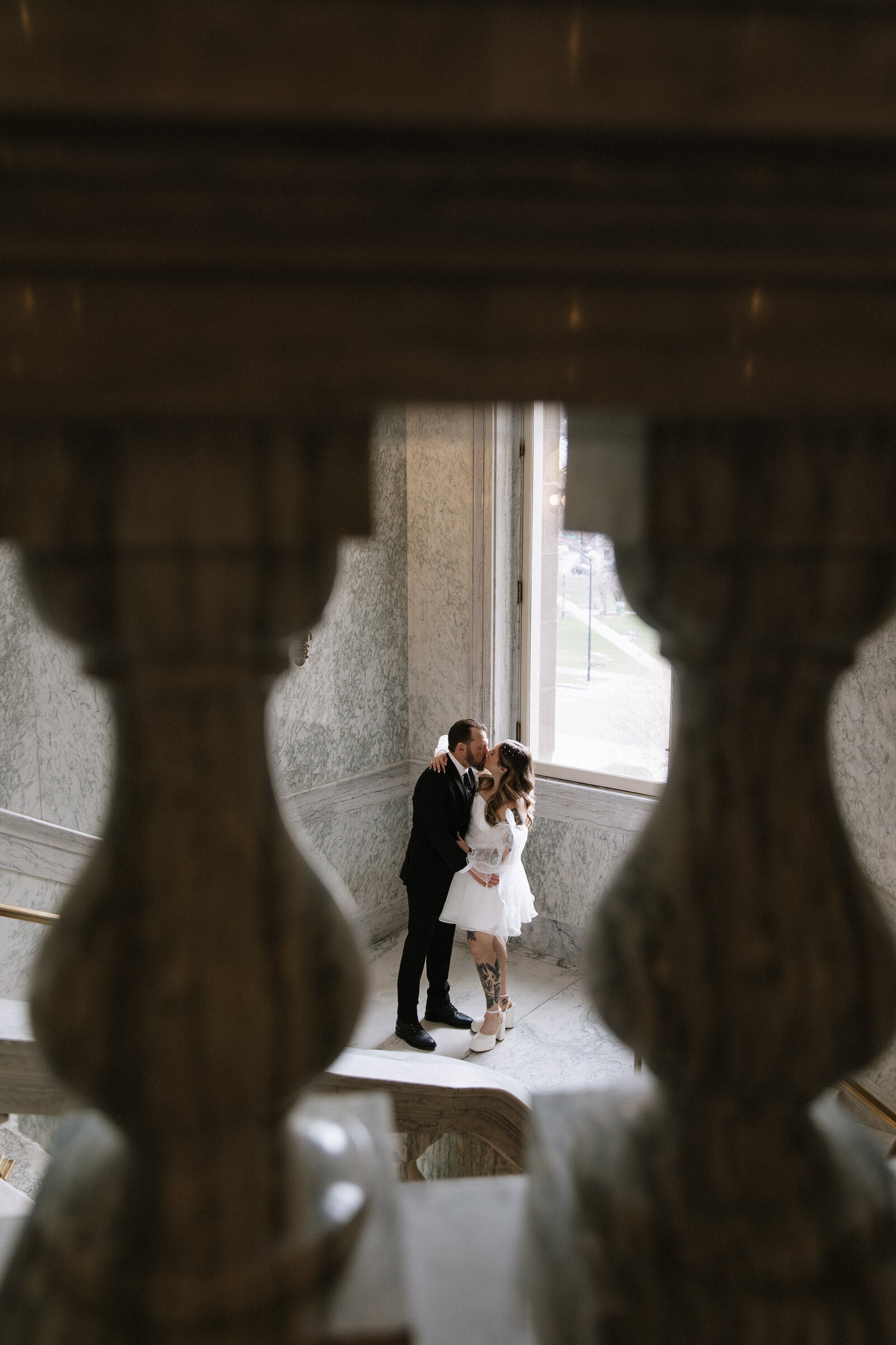 Bride and groom framed by architecture and soft light inside the Capitol