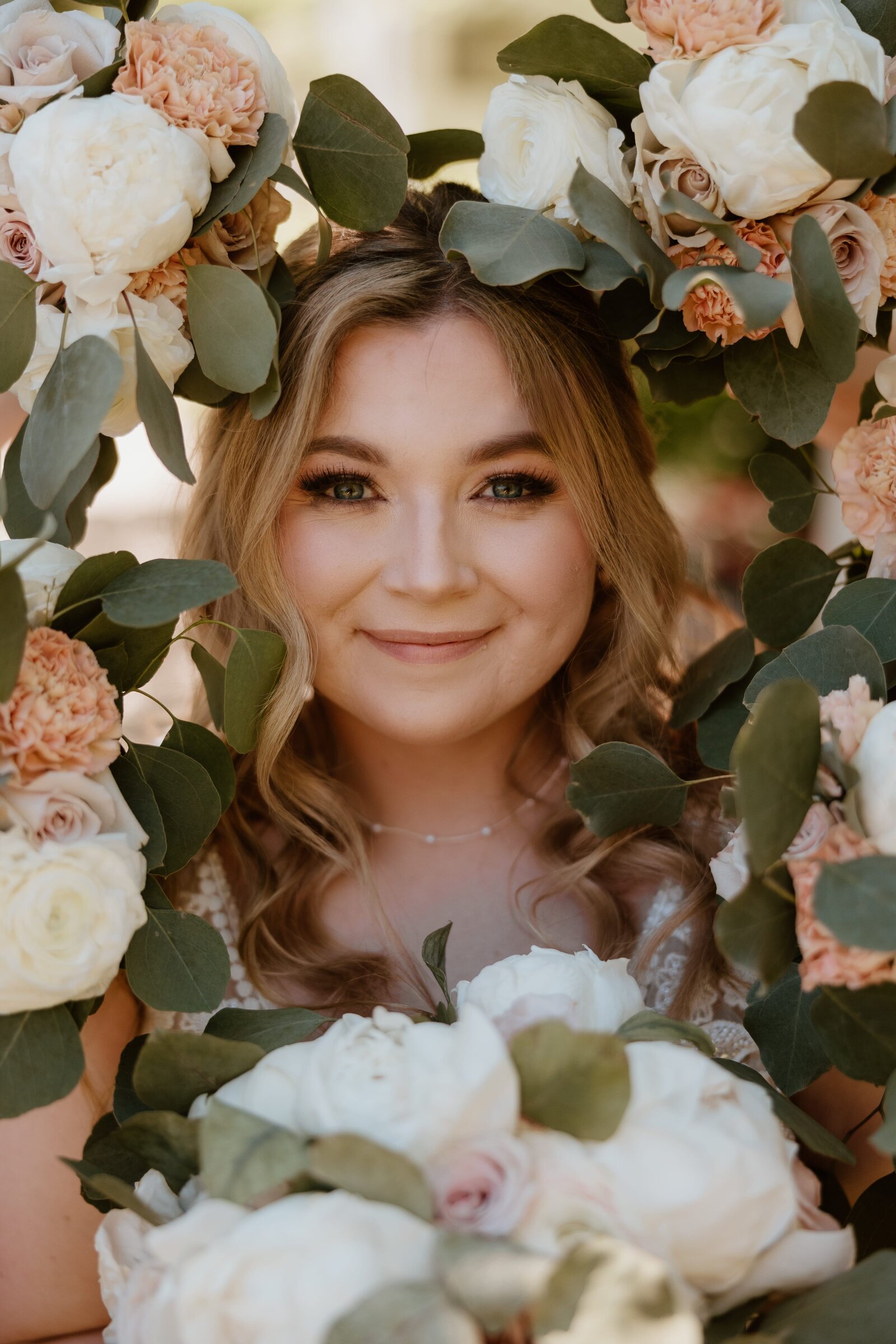 Smiling bride surrounded by floral arrangements, captured by a Hudson Valley wedding photographer.