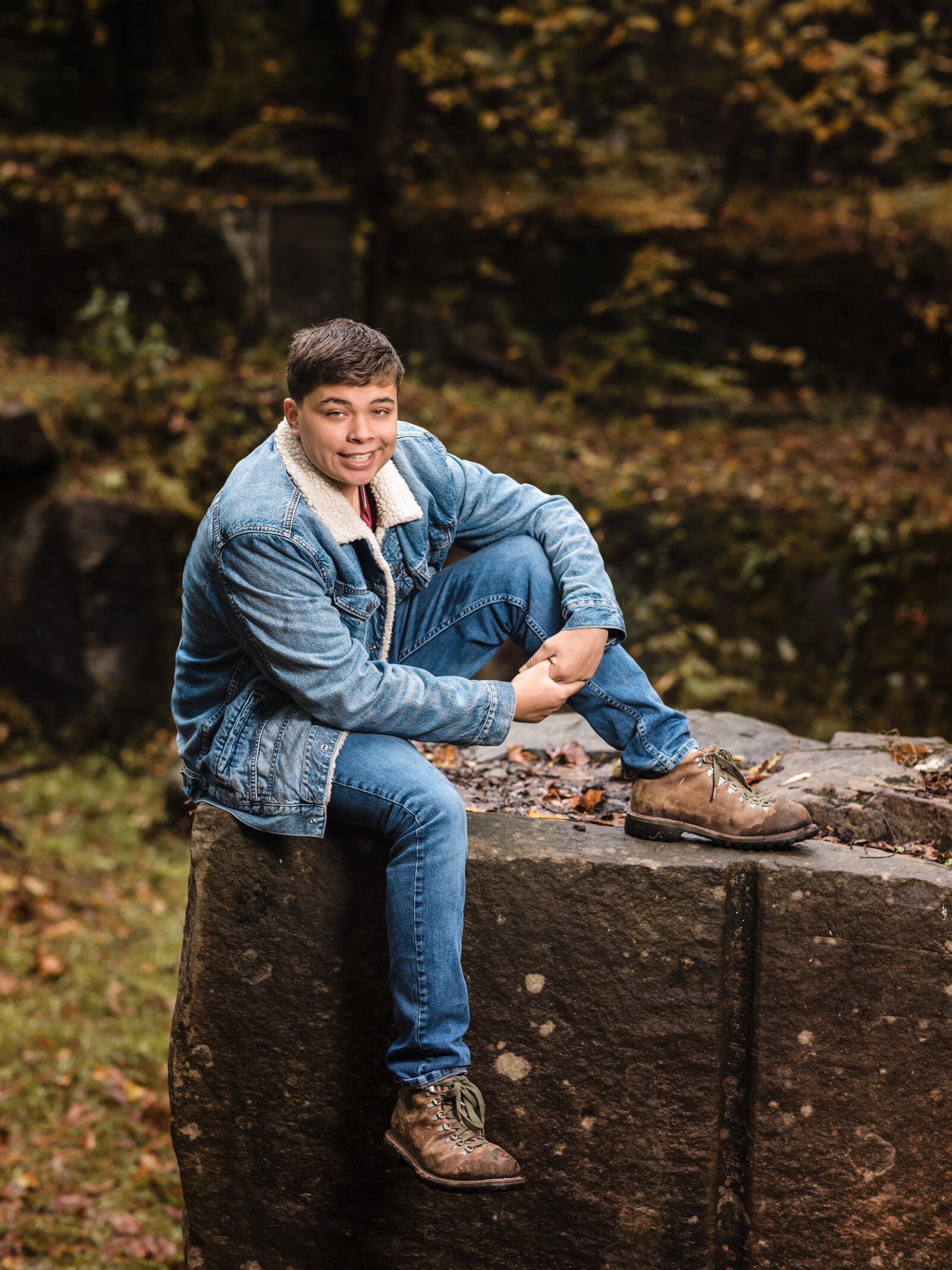 high school senior boy sitting on rock for senior portraits