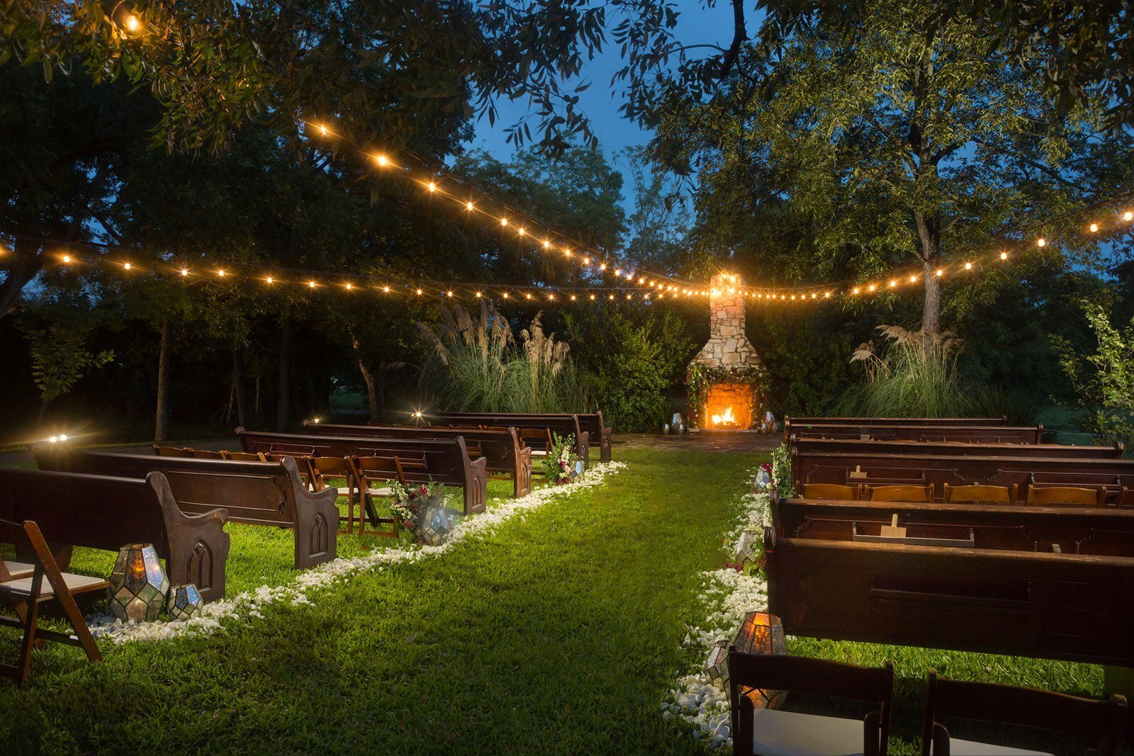 Ceremony aisle with lights and fire pit at hill country wedding venue