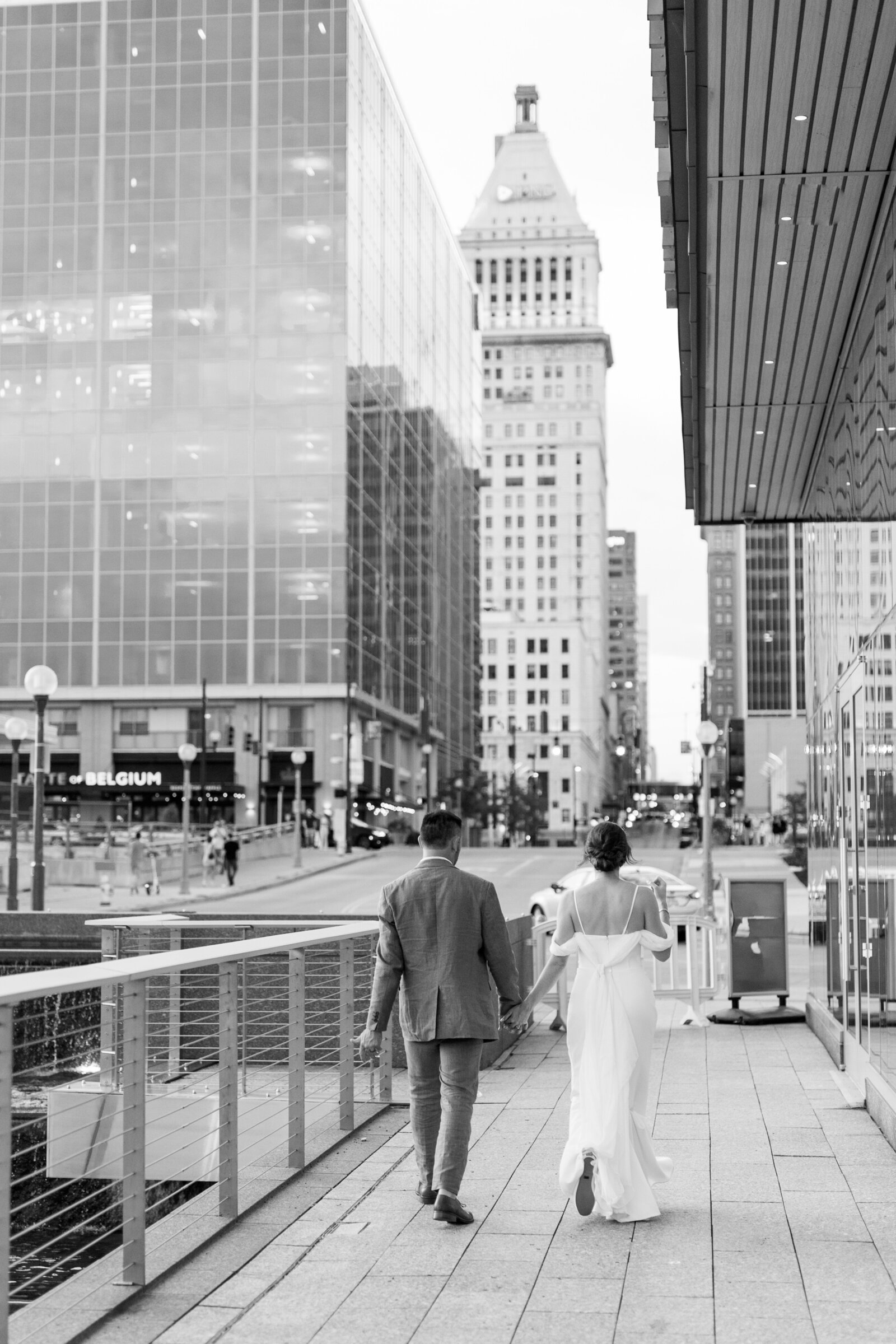 bride and groom walk toward city skyline