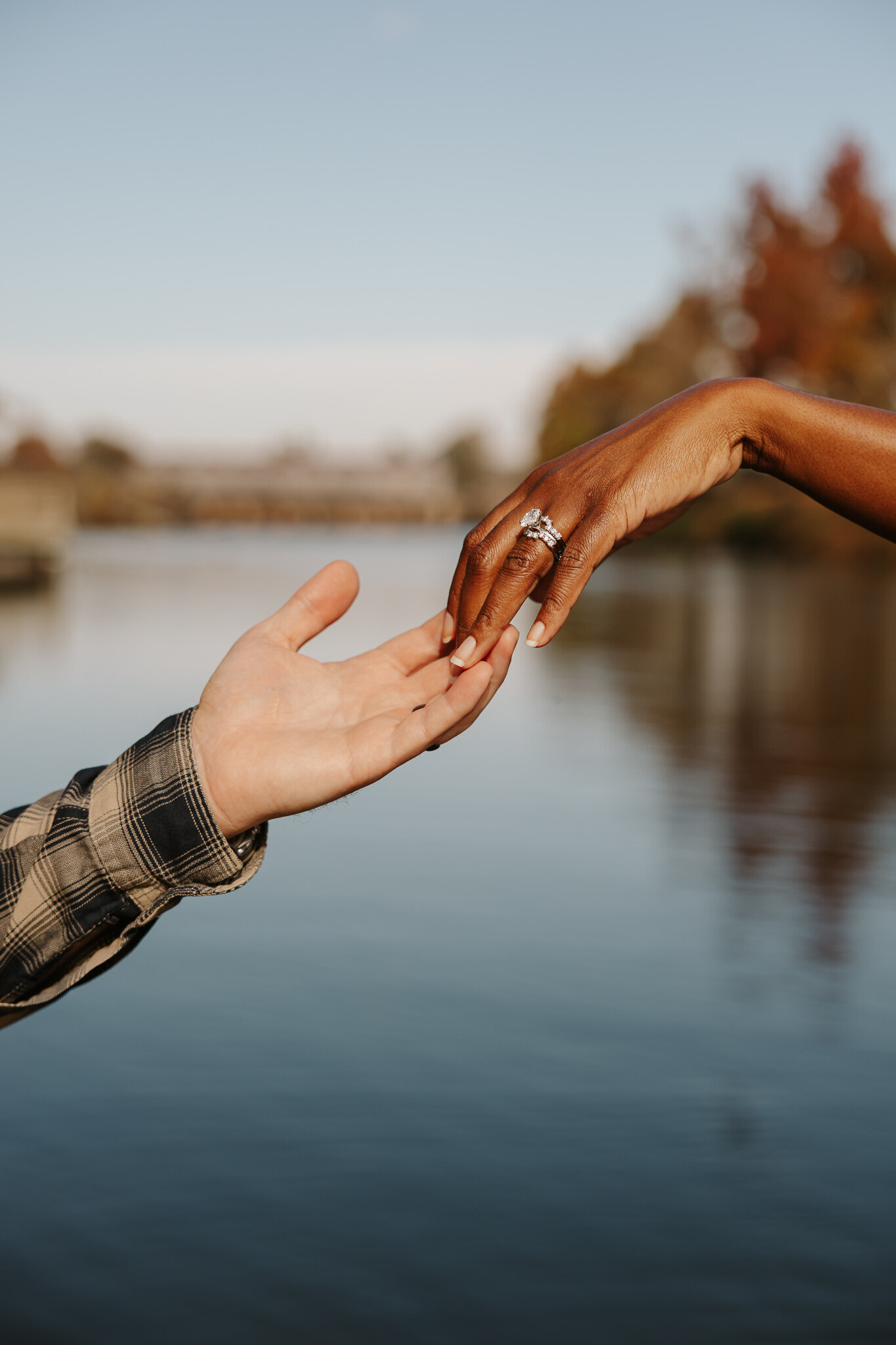 Close-up of a couple holding hands during a romantic session at Savannah Rapids in Evans Ga, with the river in the background.
