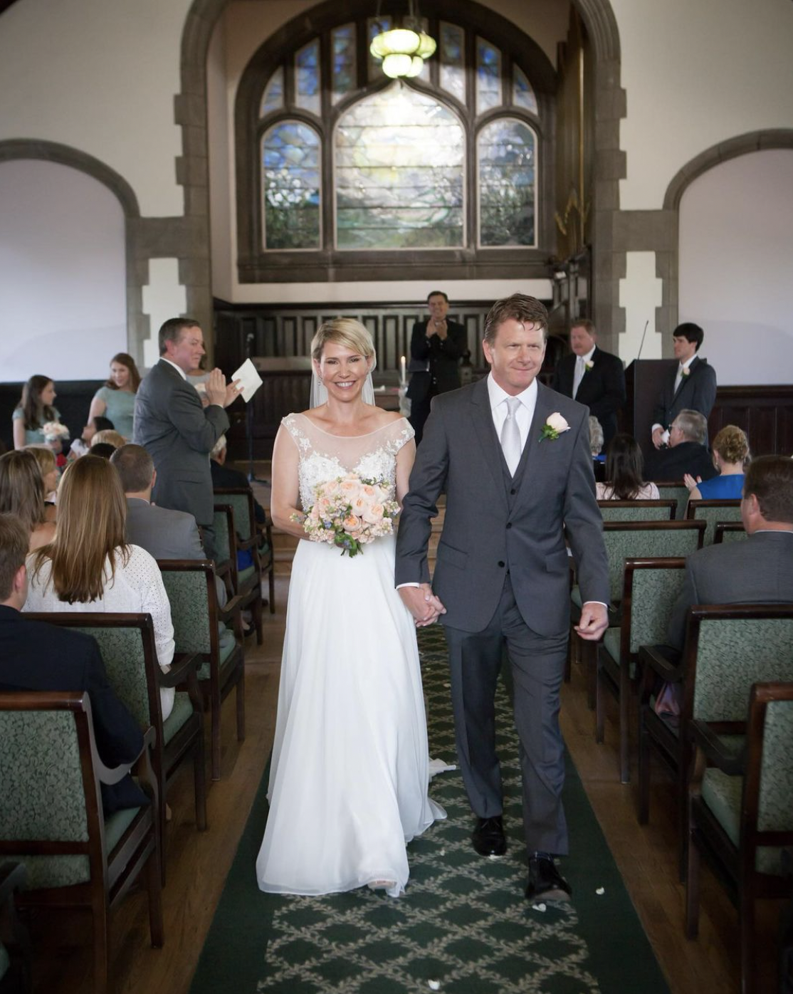 Bride and groom smile brightly as they walk back down the aisle as a married couple