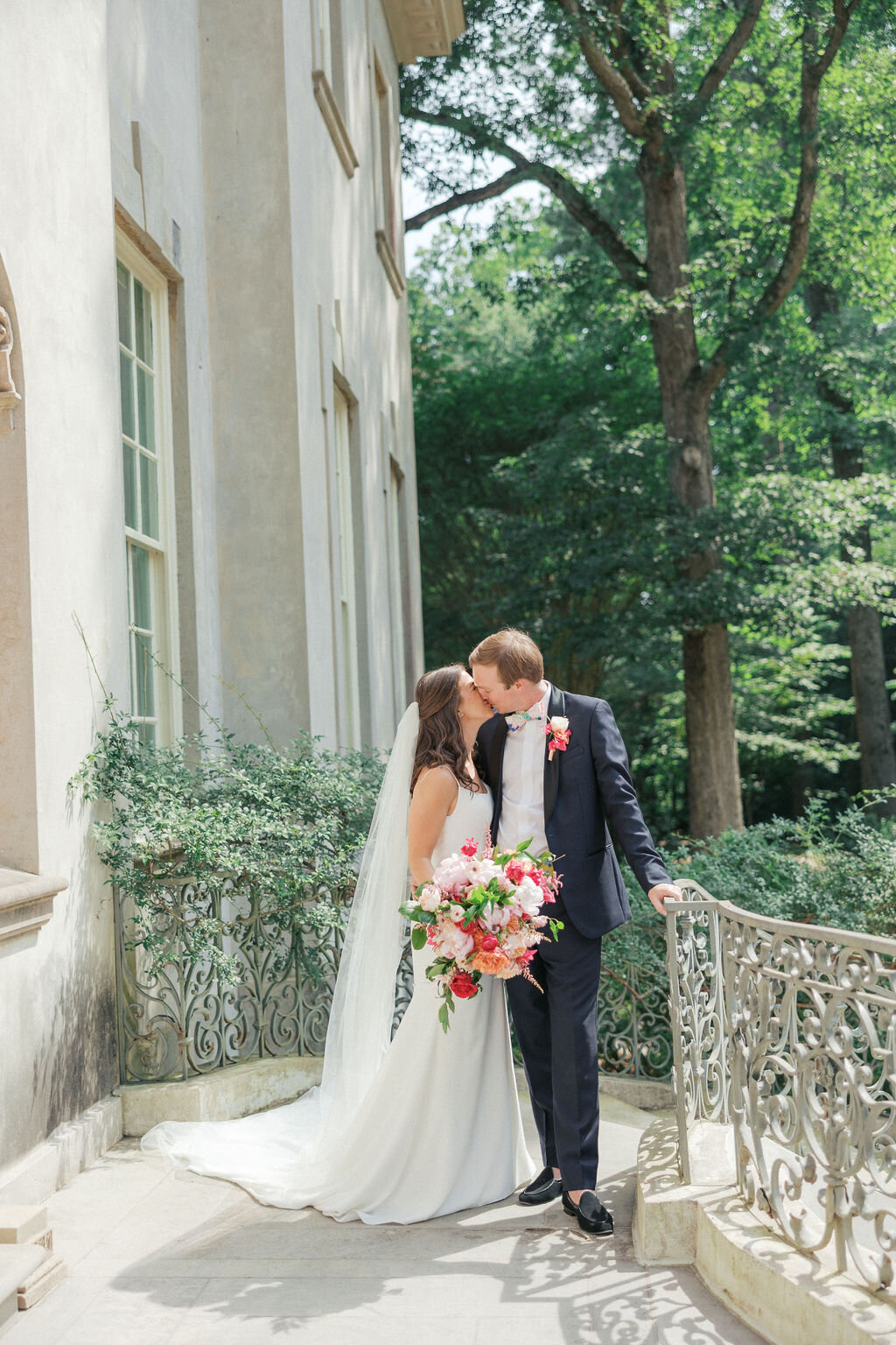 Bride and groom kiss on the back steps of the Swan House