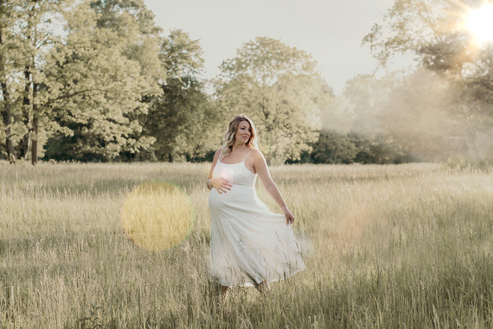 Pregnant mom, maternity session, wearing a white long dress, walking in a field of long grass at Stoney Creek Metro Park