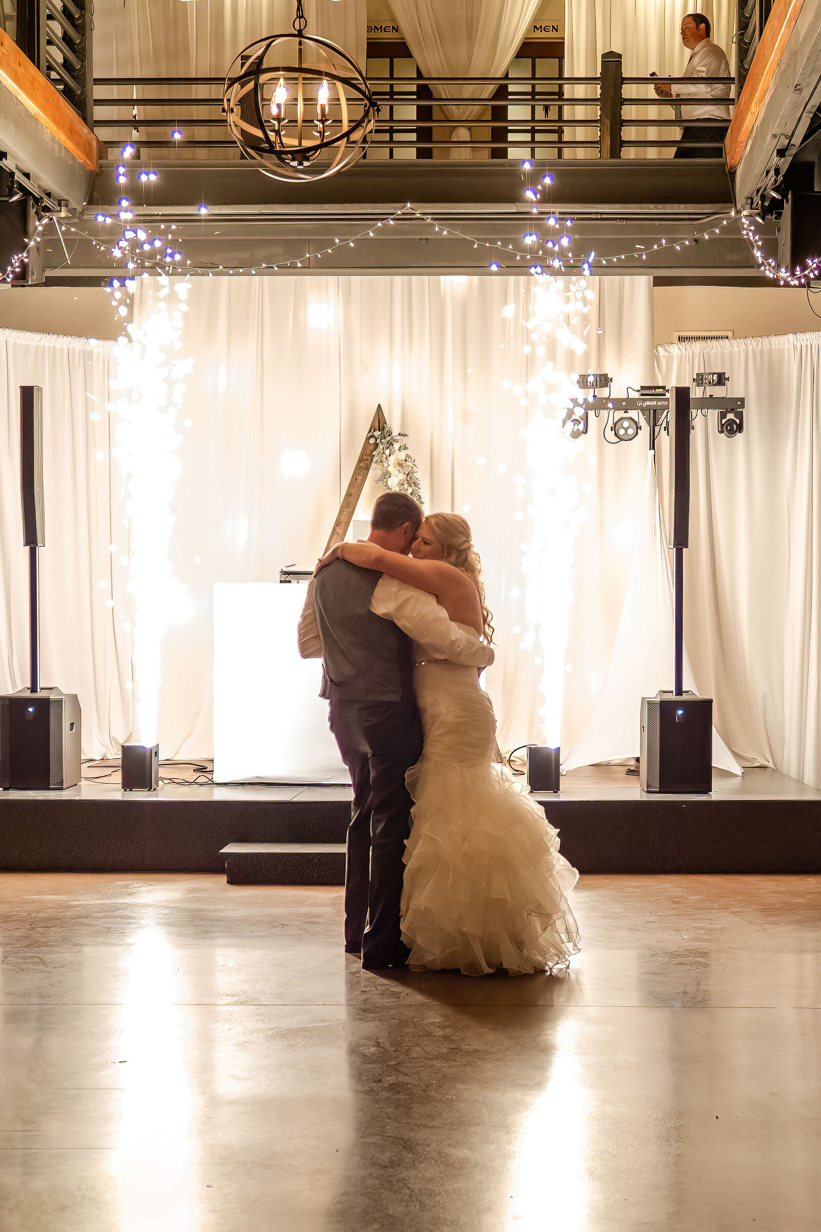 A bride and groom share their first dance surrounded by sparkling light effects and elegant drapery, captured at a Wilmington, NC wedding, blending romance and high-end wedding decor.