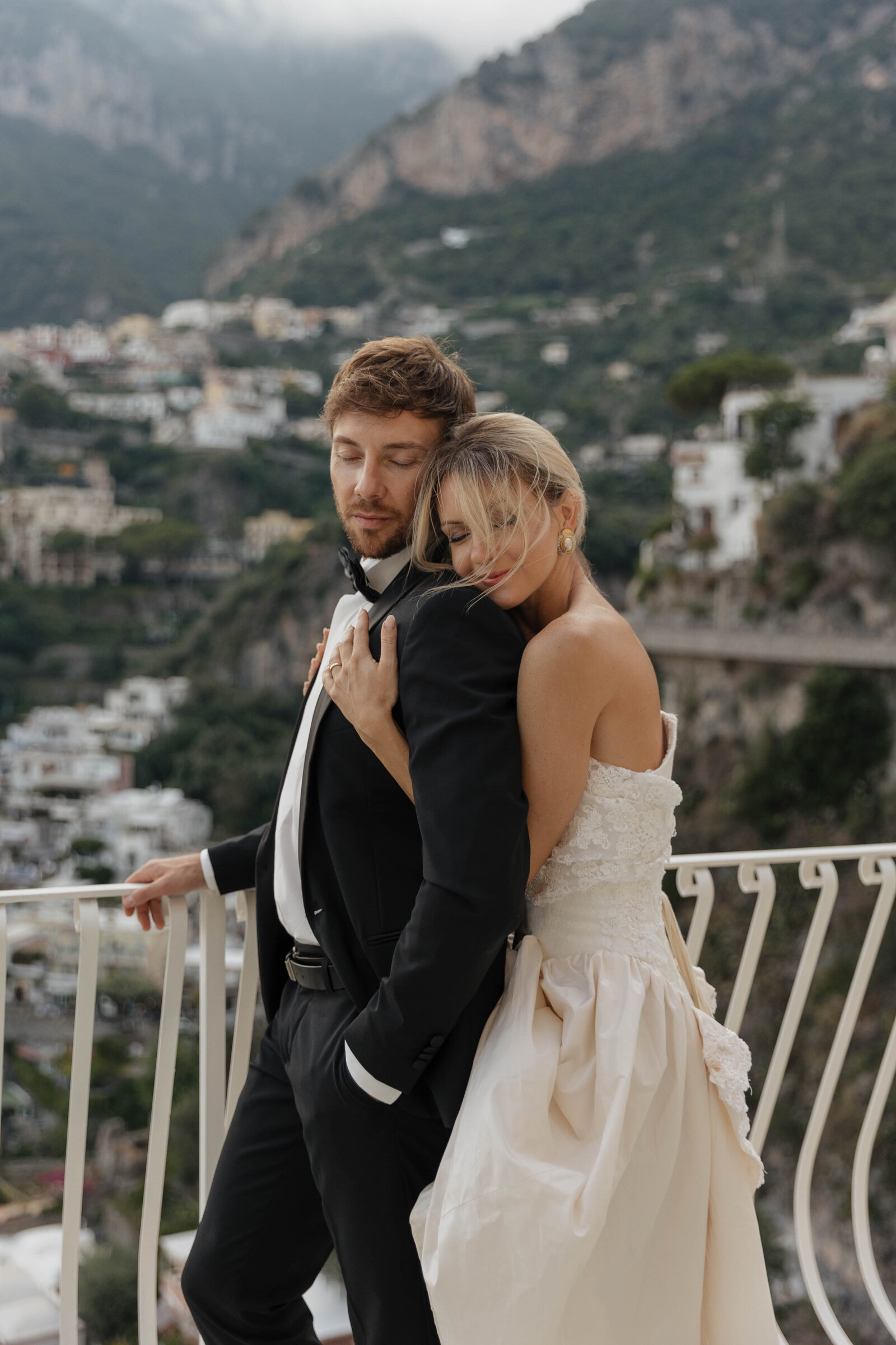 A couple embraces while an elopement photographer captures the intimate moment on the coast.