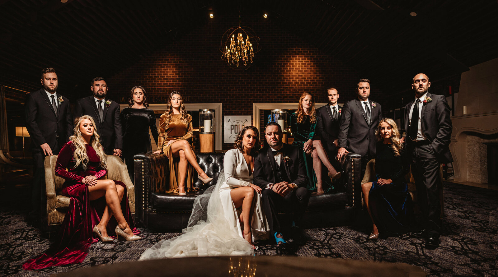 Bride and groom sitting together in a lounge surrounded by their bridal party captured by Baltimore photographers