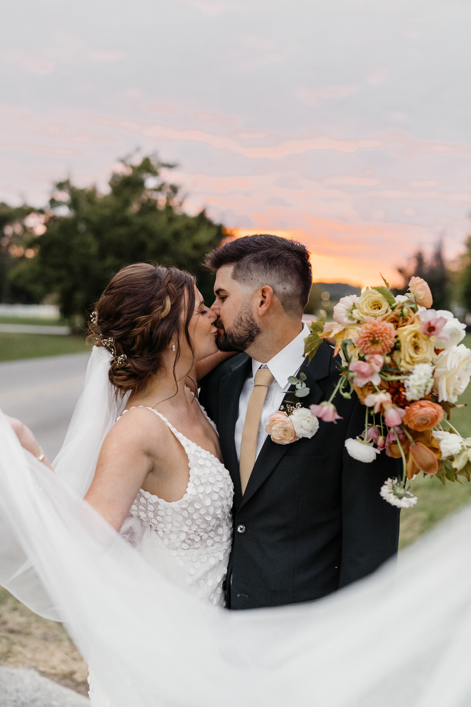 Oklahoma couple gazing lovingly at each other during their sunset engagement session in Tulsa, framed by the vibrant colors of the evening sky.