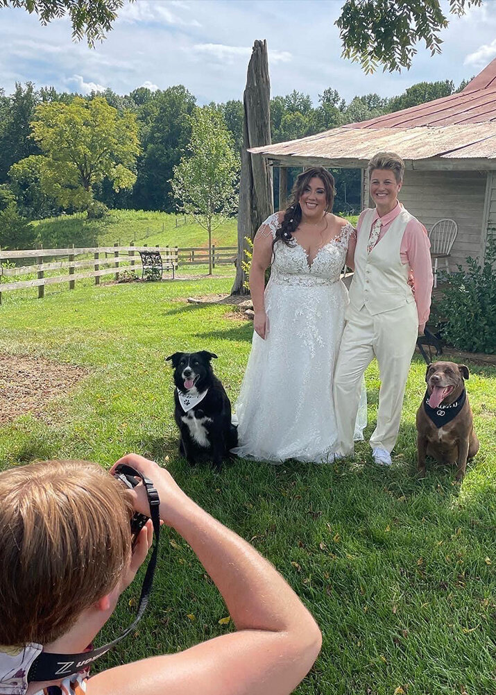 A Virginia wedding photographer takes a photo of a lesbian couple with their two dogs on their wedding day at the Pavilion at Black Water Junction.