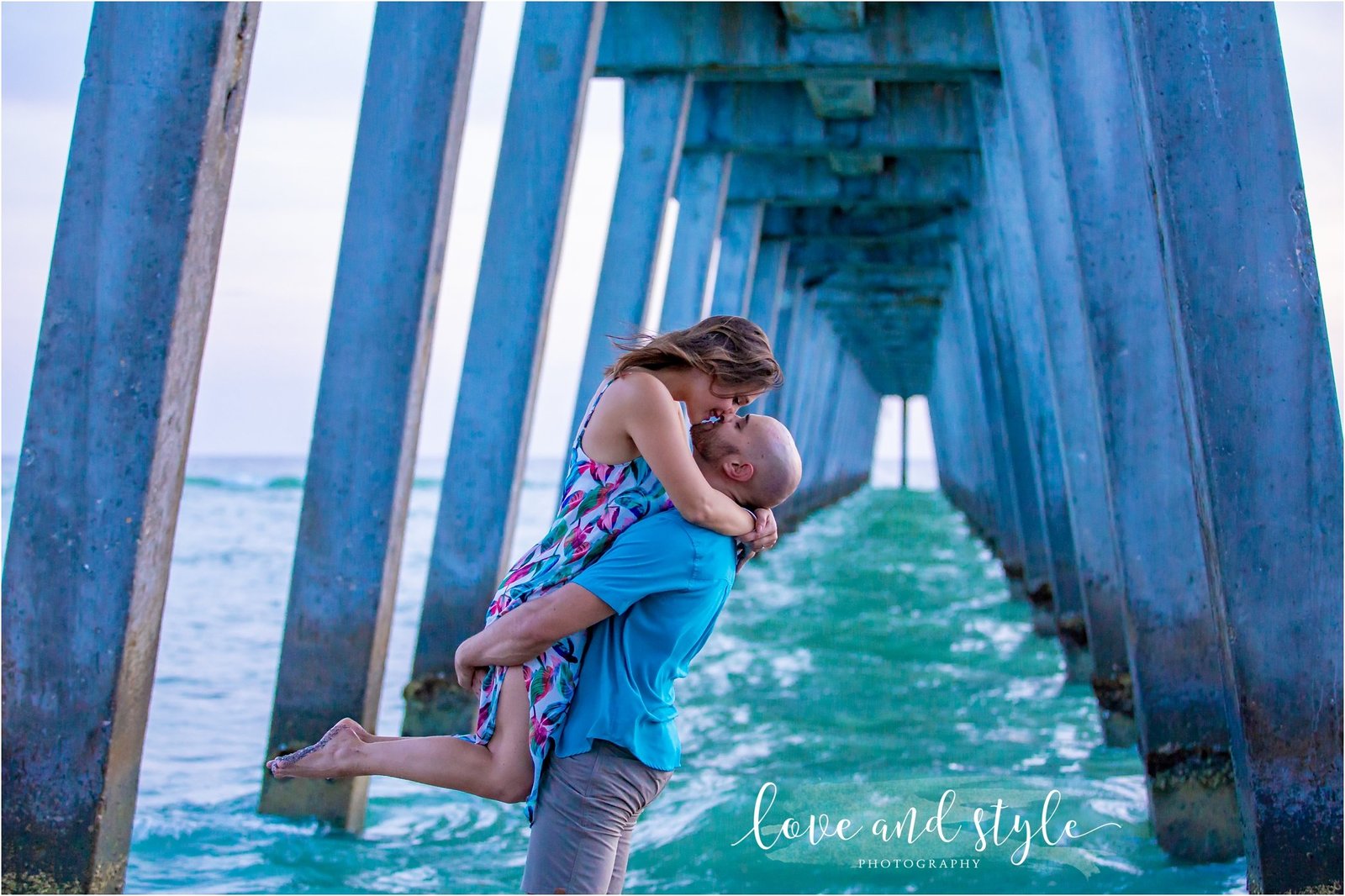 Engagement Photography on Venice Dog Beach under the pier and couple kissing